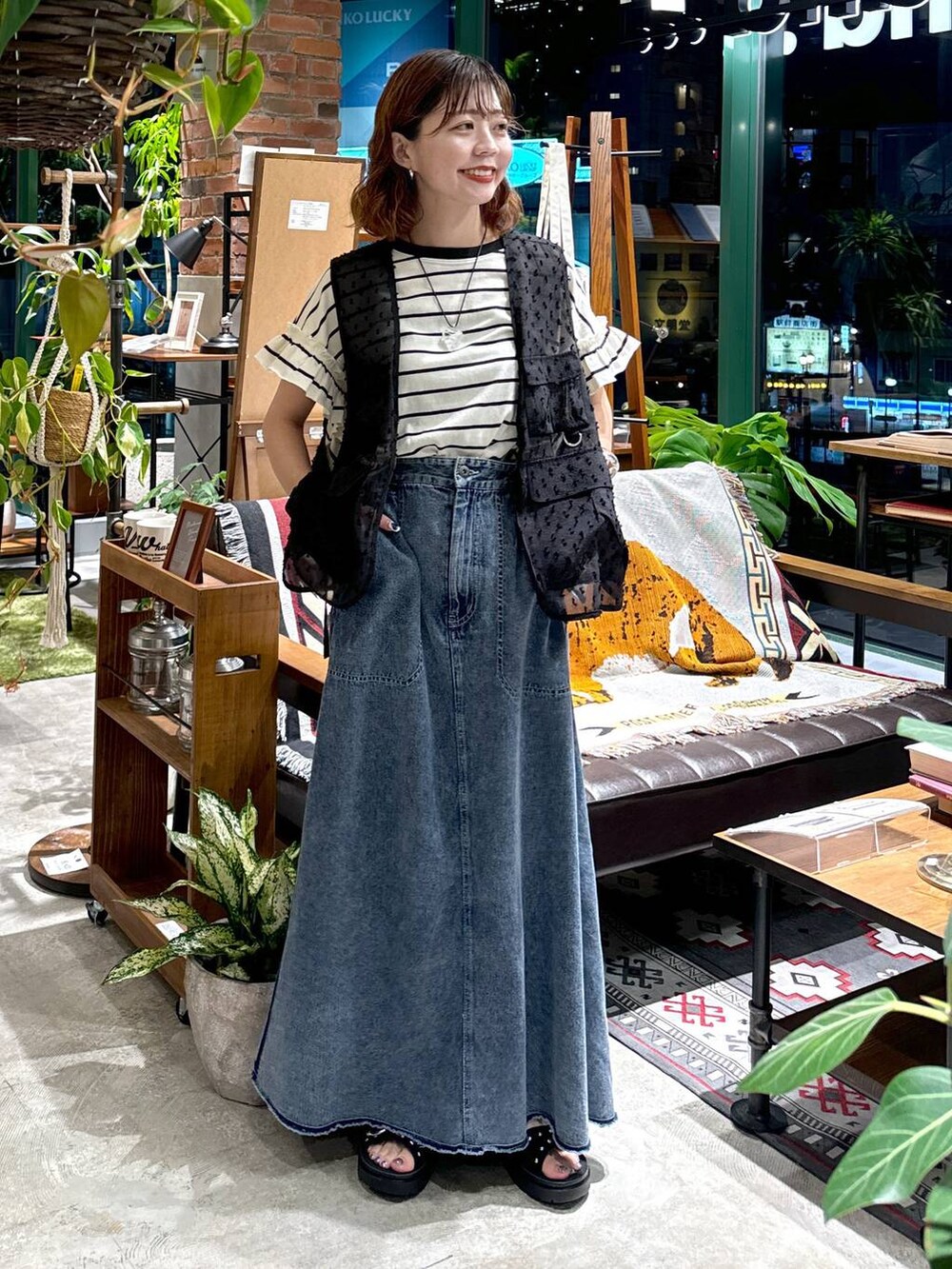 ブラック系のサンダル、ブラック系のベスト、ブルー系のスカートを着用したレディースの夏コーディネートの2枚目の写真