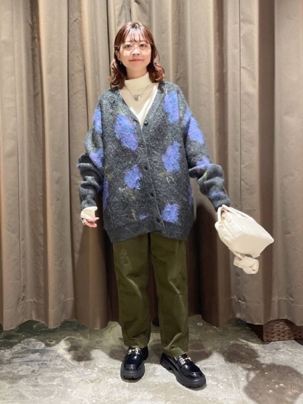 ベージュ系のニット/セーター、ブラック系のローファー、ベージュ系のショルダーバッグを着用したレディースの冬コーディネートの2枚目の写真