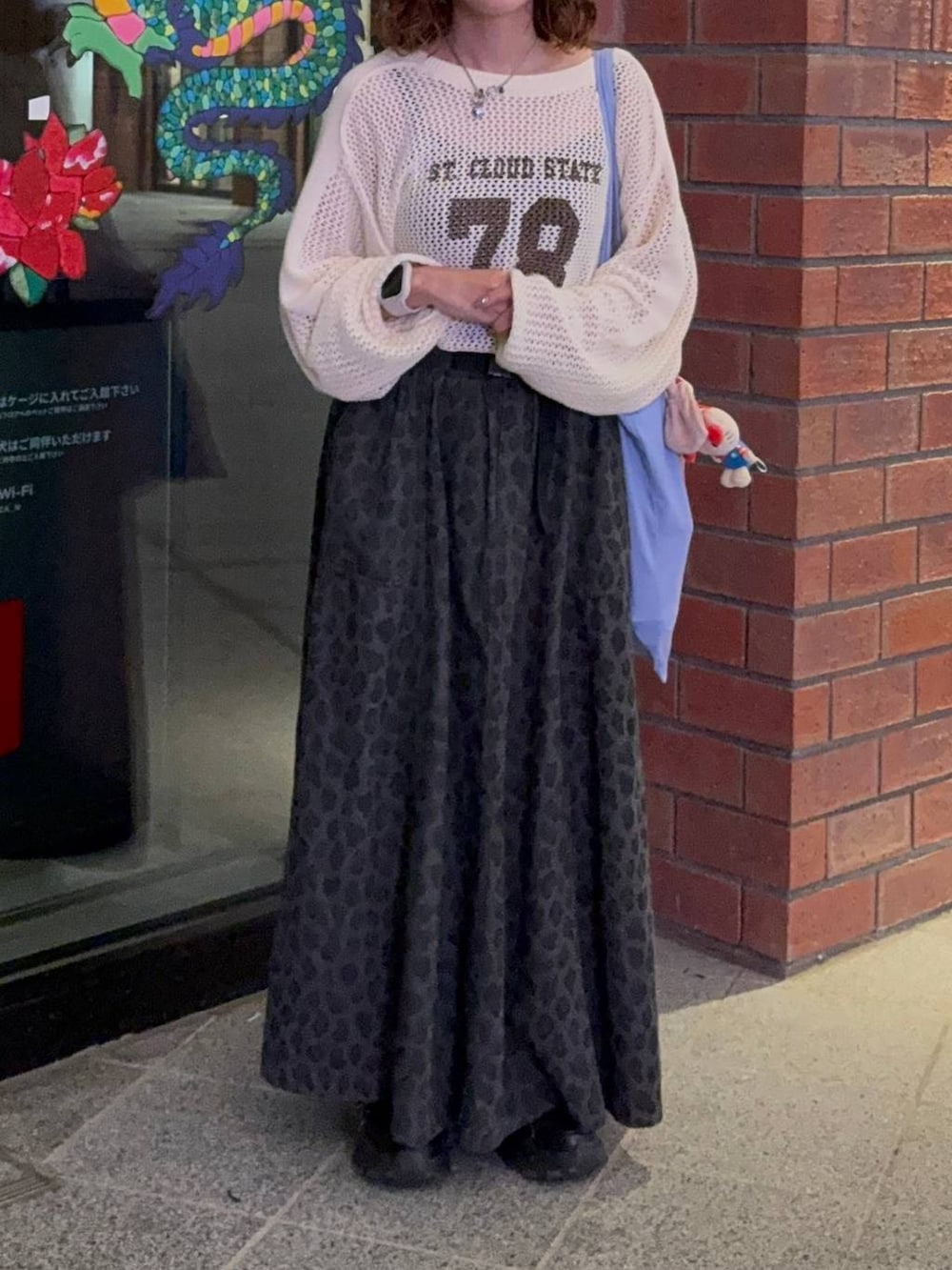 グレー系のスカート、ブラック系のスニーカー、ベージュ系のTシャツ/カットソーを着用したレディースの秋コーディネートの3枚目の写真