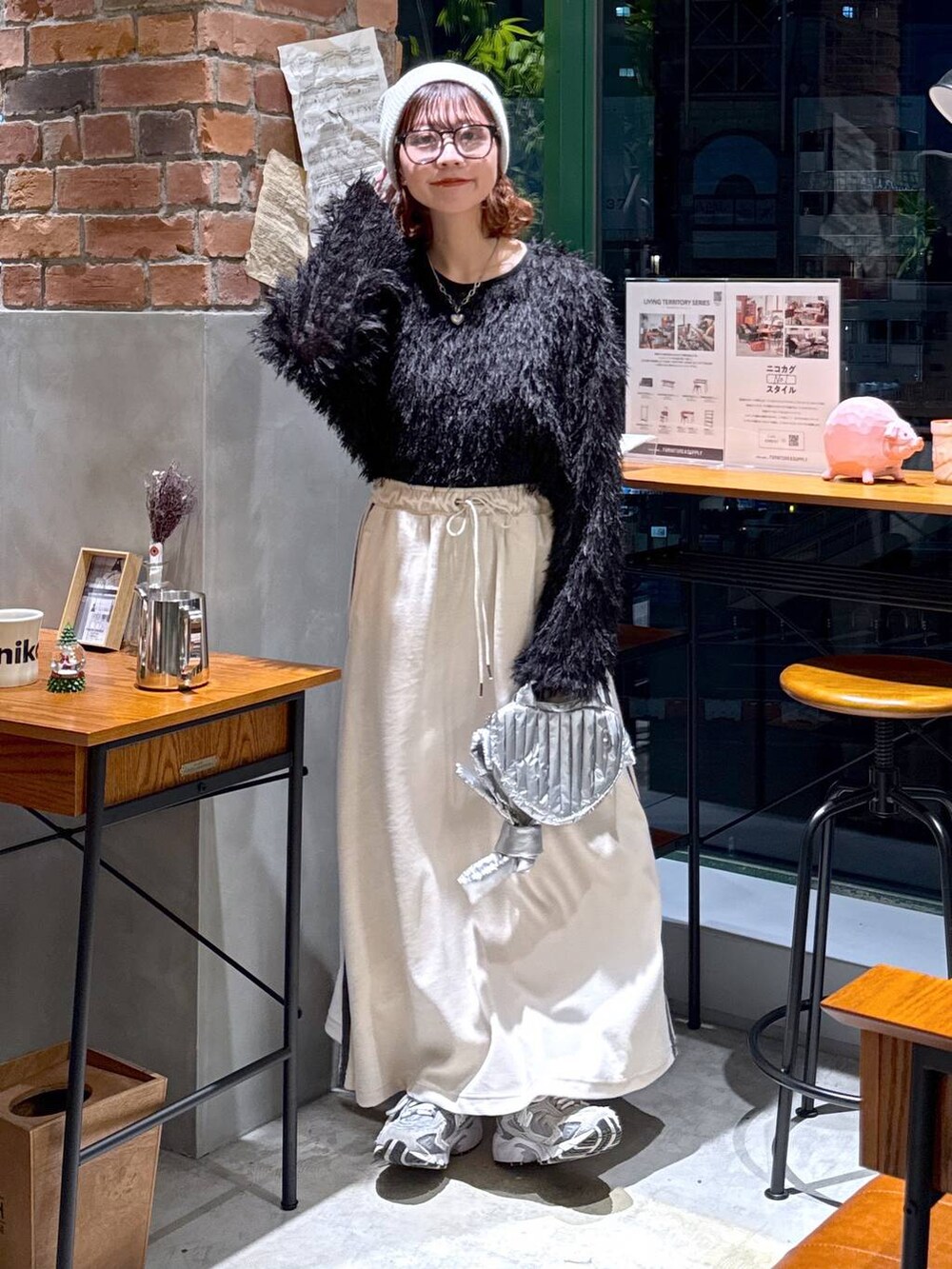 シルバー系のショルダーバッグ、ブラック系のその他トップス、ベージュ系のスカートを着用したレディースの冬コーディネートの2枚目の写真