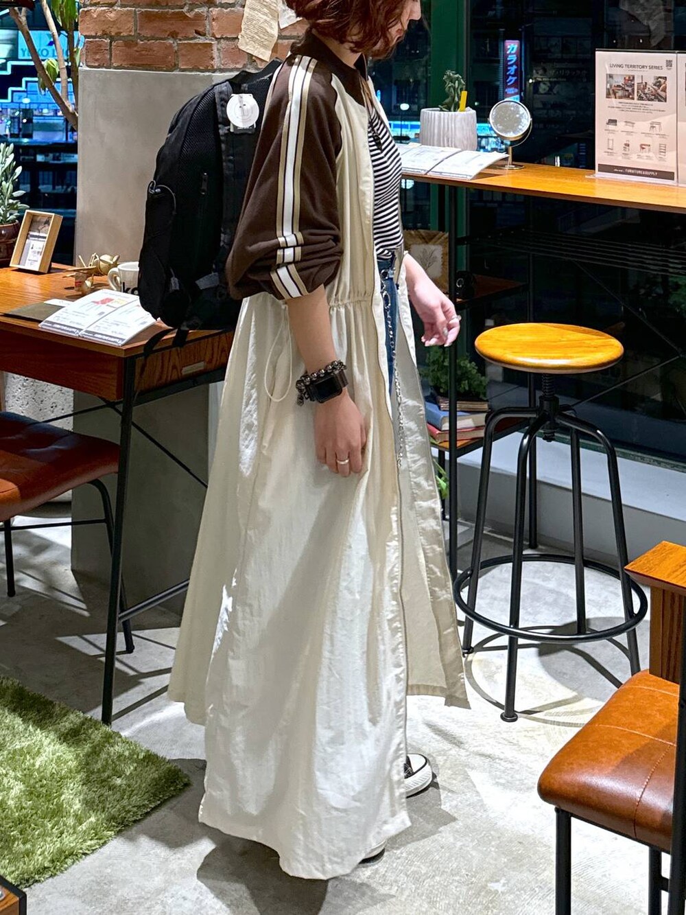 ブルー系のデニムパンツ、ベージュ系のワンピース、ホワイト系のキャミソールを着用したレディースの秋コーディネートの5枚目の写真