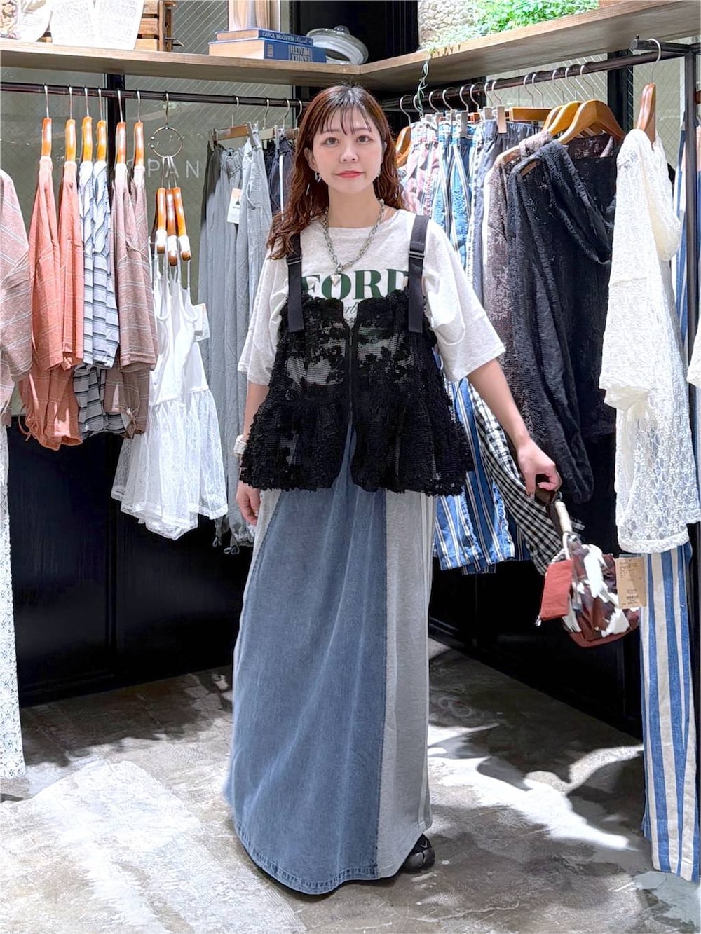 ブラック系のベスト、ベージュ系のTシャツ/カットソー、ブルー系のデニムスカートを着用したレディースの夏コーディネートの6枚目の写真