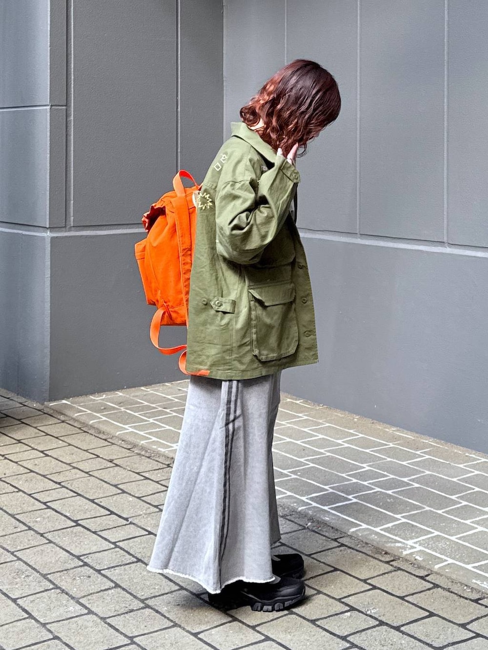 グリーン系のシャツ/ブラウス、オレンジ系のバックパック/リュック、ホワイト系のTシャツ/カットソーを着用したレディースの春コーディネートの5枚目の写真