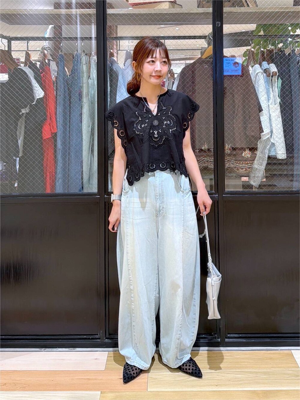 ブラック系のベスト、グリーン系のデニムパンツ、シルバー系のショルダーバッグを着用したレディースの夏コーディネートの3枚目の写真