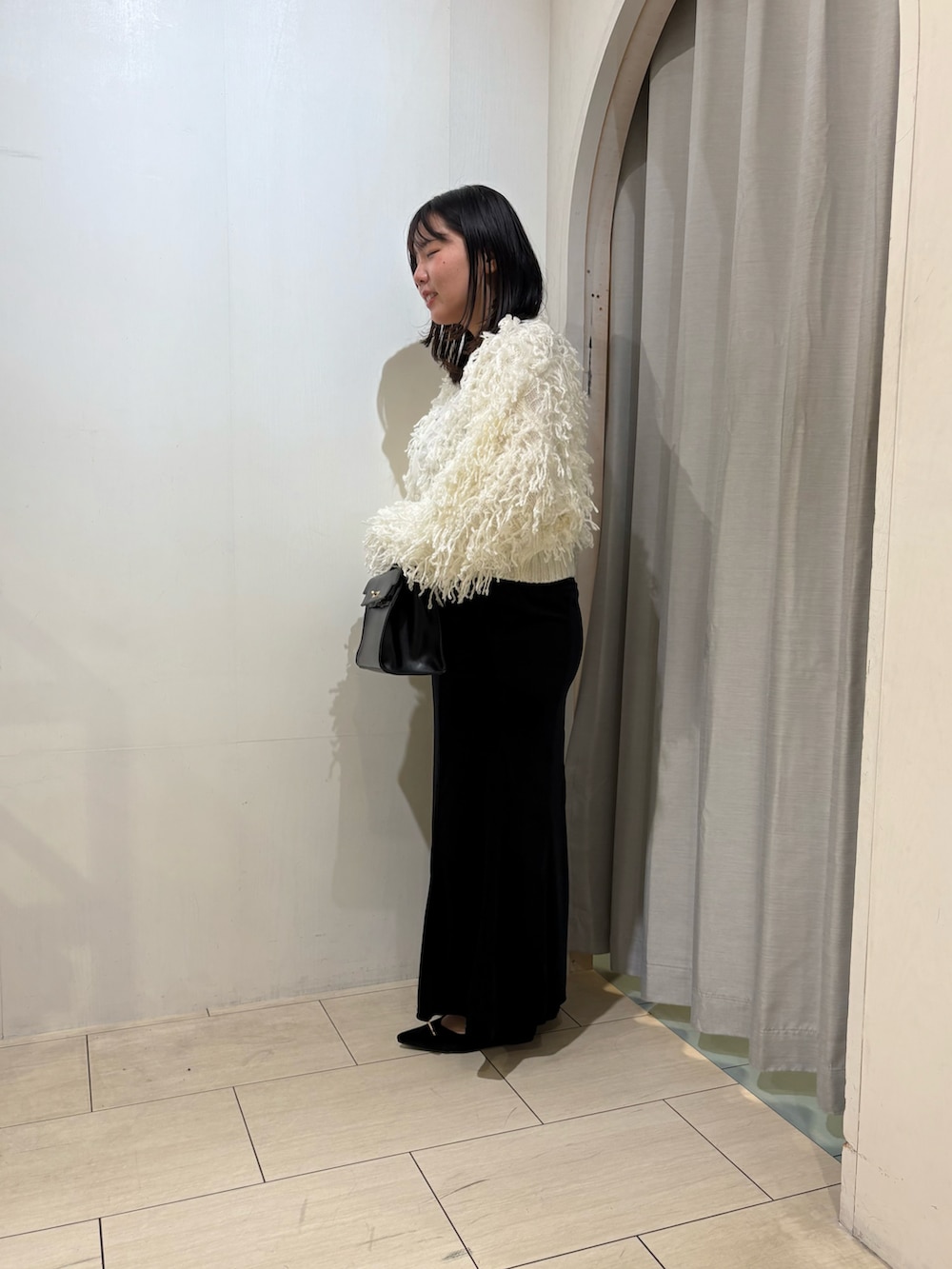 ブラック系のスカート、ブラック系のパンプス、ホワイト系のカーディガン/ボレロを着用したレディースの秋コーディネートの2枚目の写真