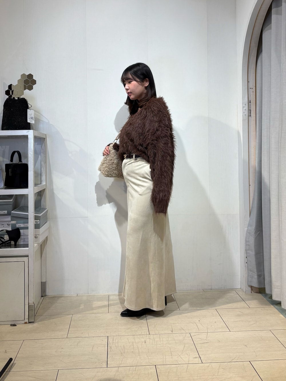 ベージュ系のスカート、ブラック系のブーツ、ブラウン系のカーディガン/ボレロを着用したレディースの秋コーディネートの2枚目の写真