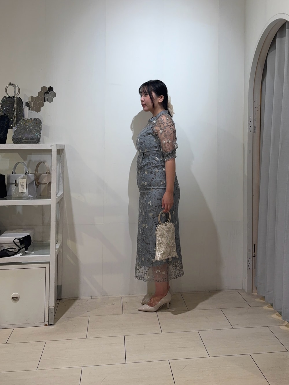 グリーン系のドレス、ベージュ系のハンドバッグ、ゴールド系のパンプスを着用したレディースの秋コーディネートの2枚目の写真