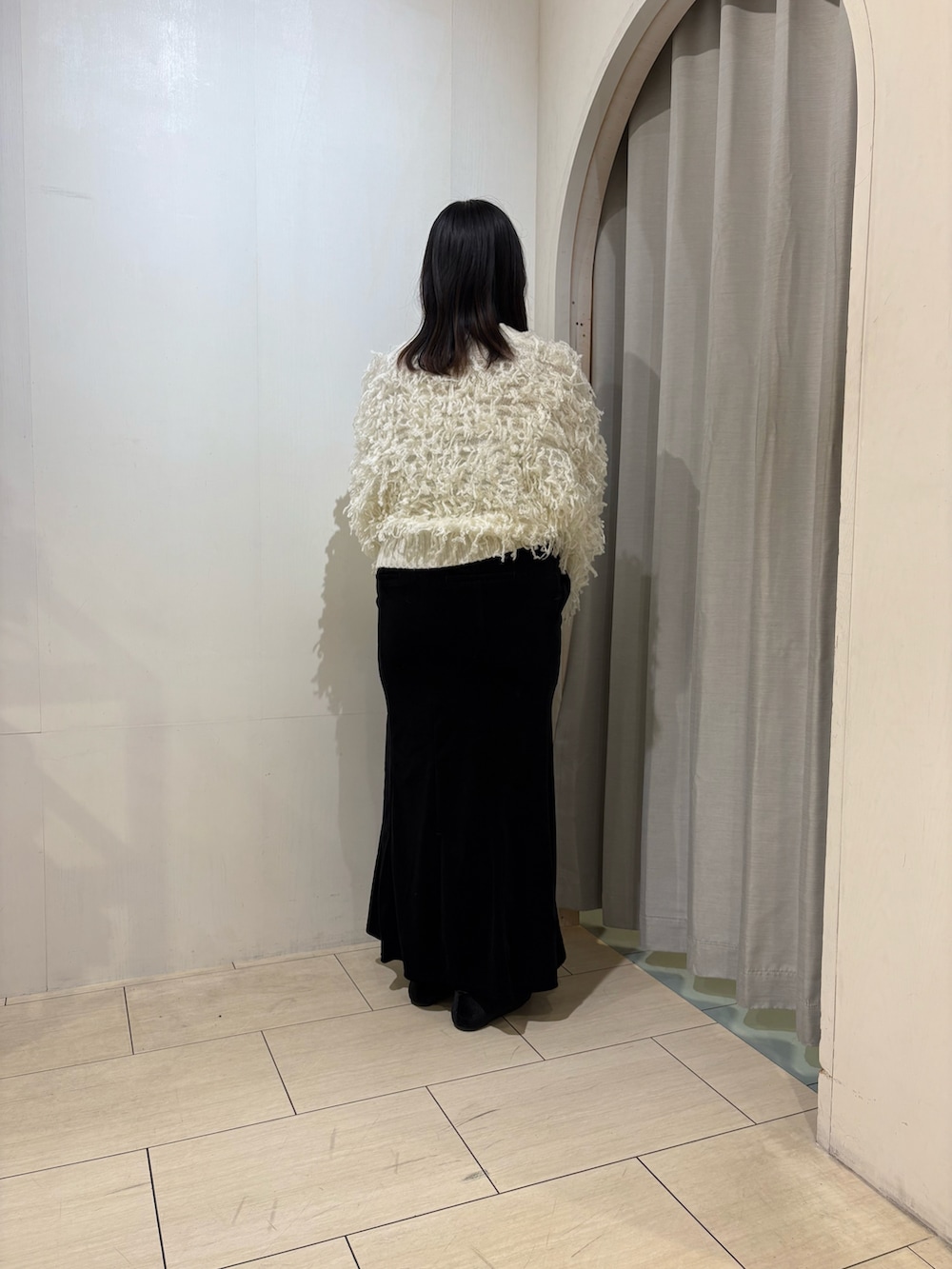 ブラック系のスカート、ブラック系のパンプス、ホワイト系のカーディガン/ボレロを着用したレディースの秋コーディネートの3枚目の写真