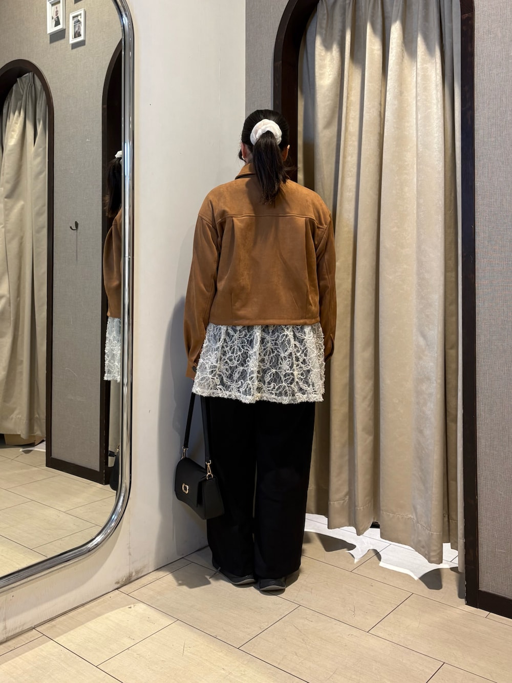 イエロー系のブルゾン、ブラック系のショルダーバッグ、ホワイト系のチュニックを着用したレディースの冬コーディネートの3枚目の写真