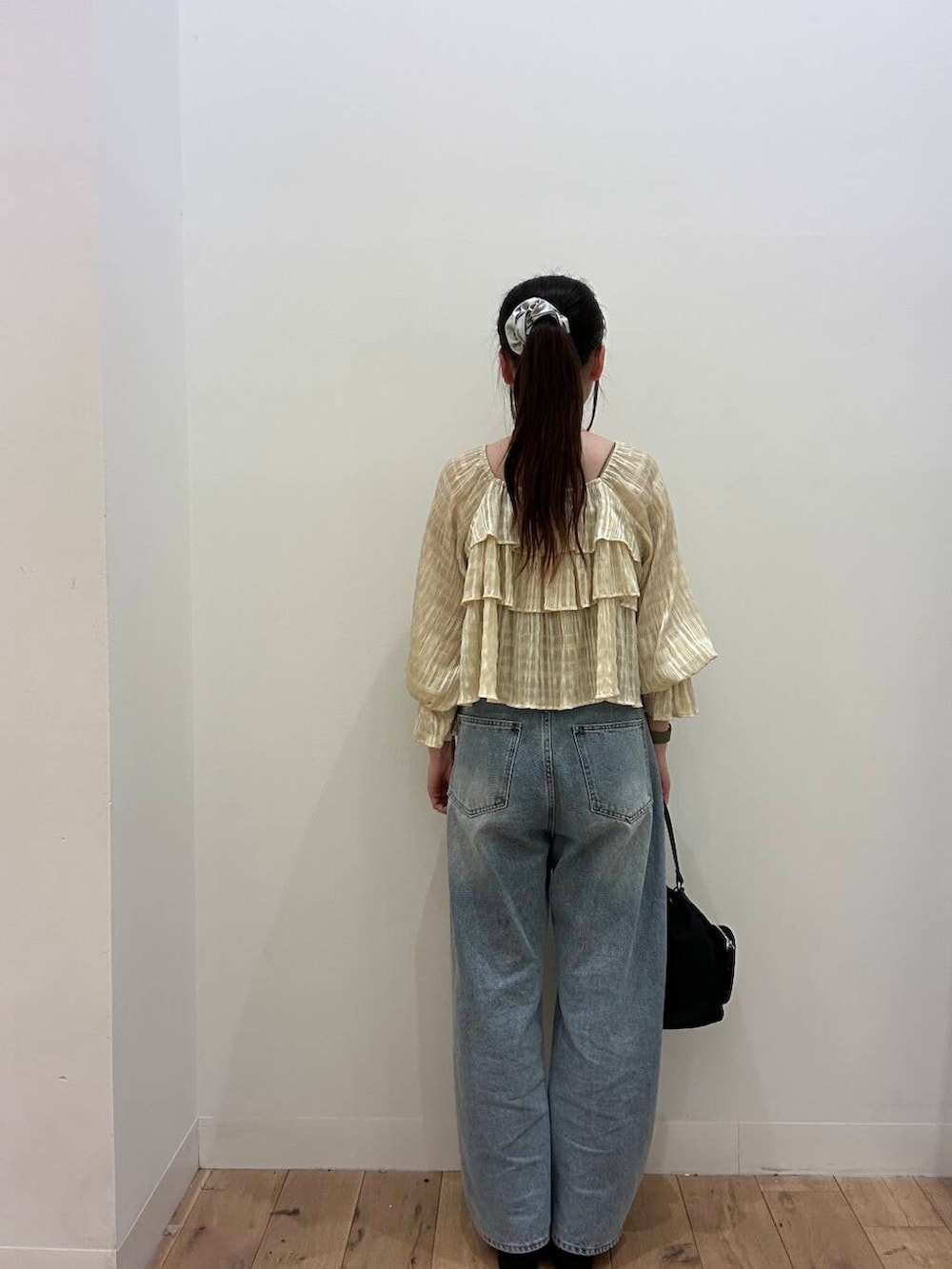 ブラック系のショルダーバッグ、ブラウン系のキャミソール、ブルー系のデニムパンツを着用したレディースの春コーディネートの3枚目の写真