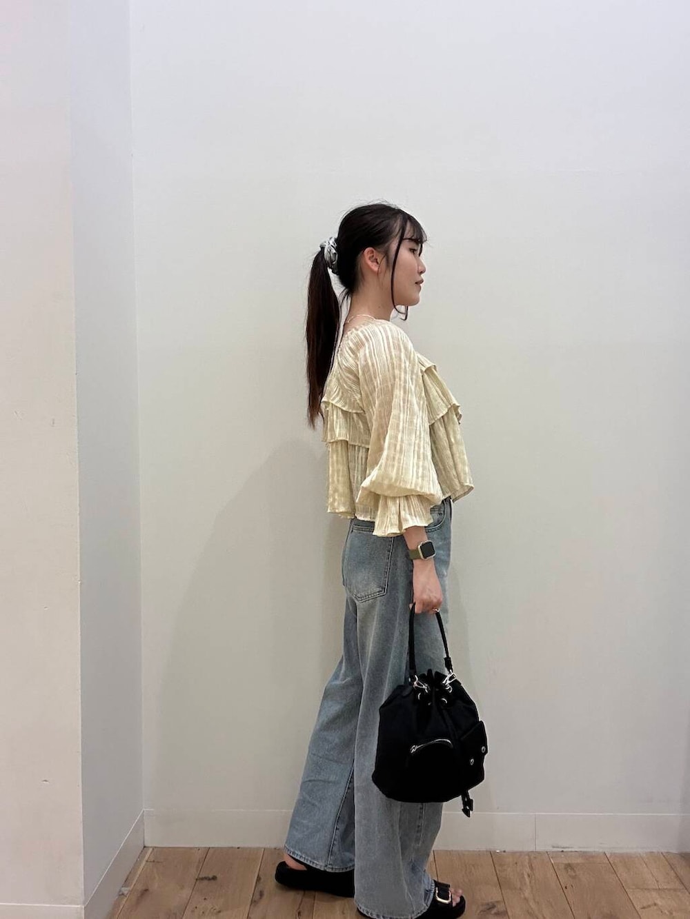 ブラック系のショルダーバッグ、ブラウン系のキャミソール、ブルー系のデニムパンツを着用したレディースの春コーディネートの2枚目の写真