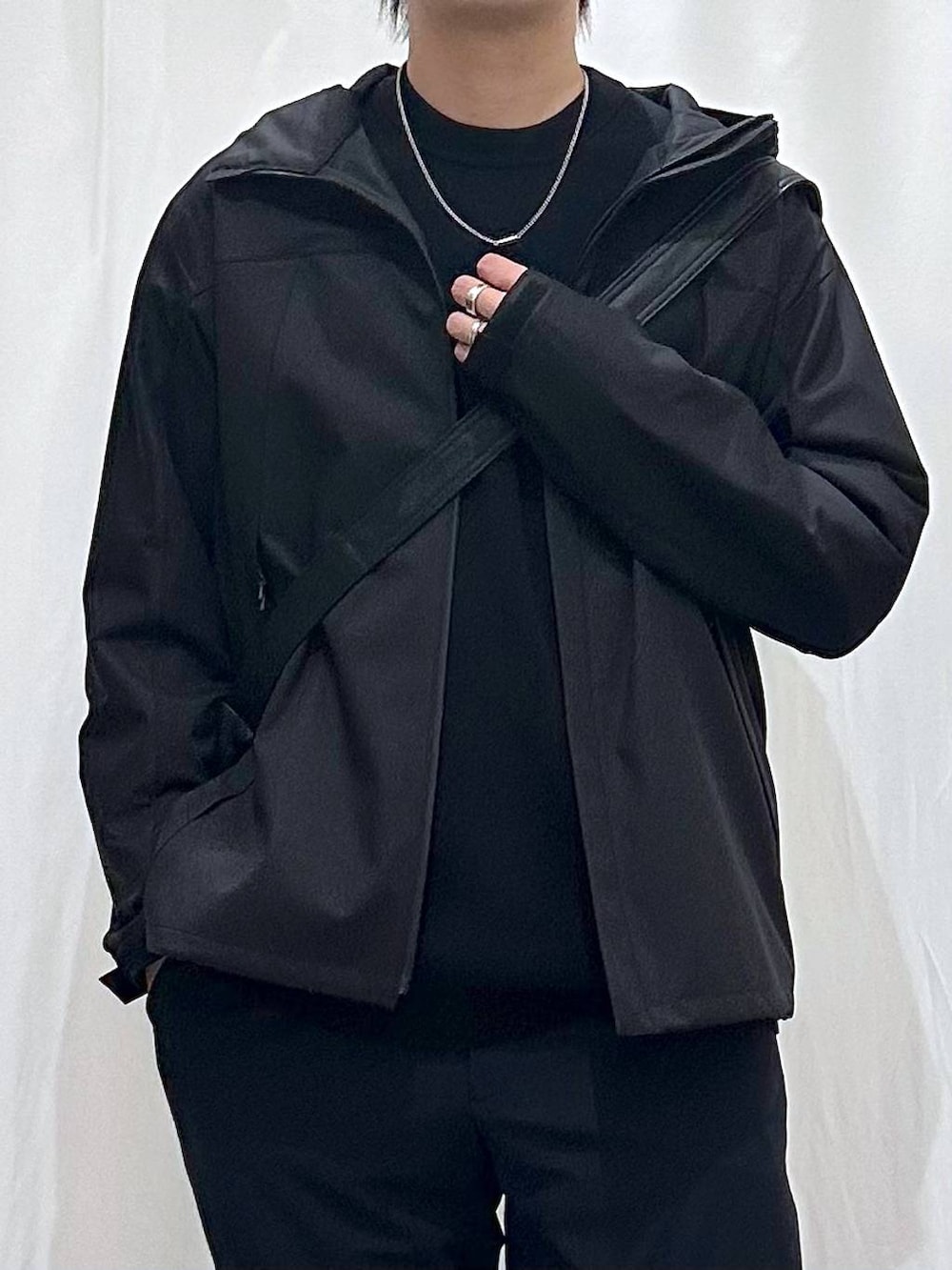 ブルー系のスラックス、ブラック系のニット/セーター、ブラック系のショルダーバッグを着用したメンズの春コーディネートの2枚目の写真