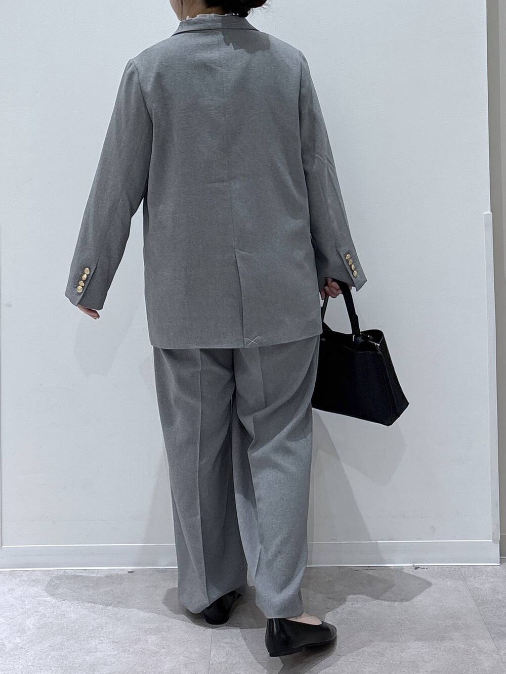 ブラック系のパンプス、ブラック系のショルダーバッグ、グレー系のテーラードジャケットを着用したレディースの冬コーディネートの3枚目の写真