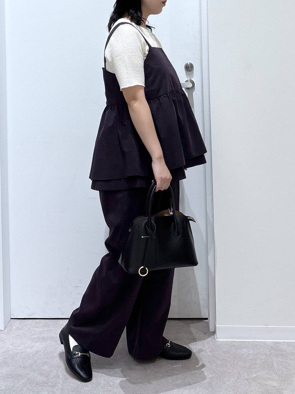 ブラック系のローファー、ブラック系のショルダーバッグ、ホワイト系のTシャツ/カットソーを着用したレディースの夏コーディネートの2枚目の写真