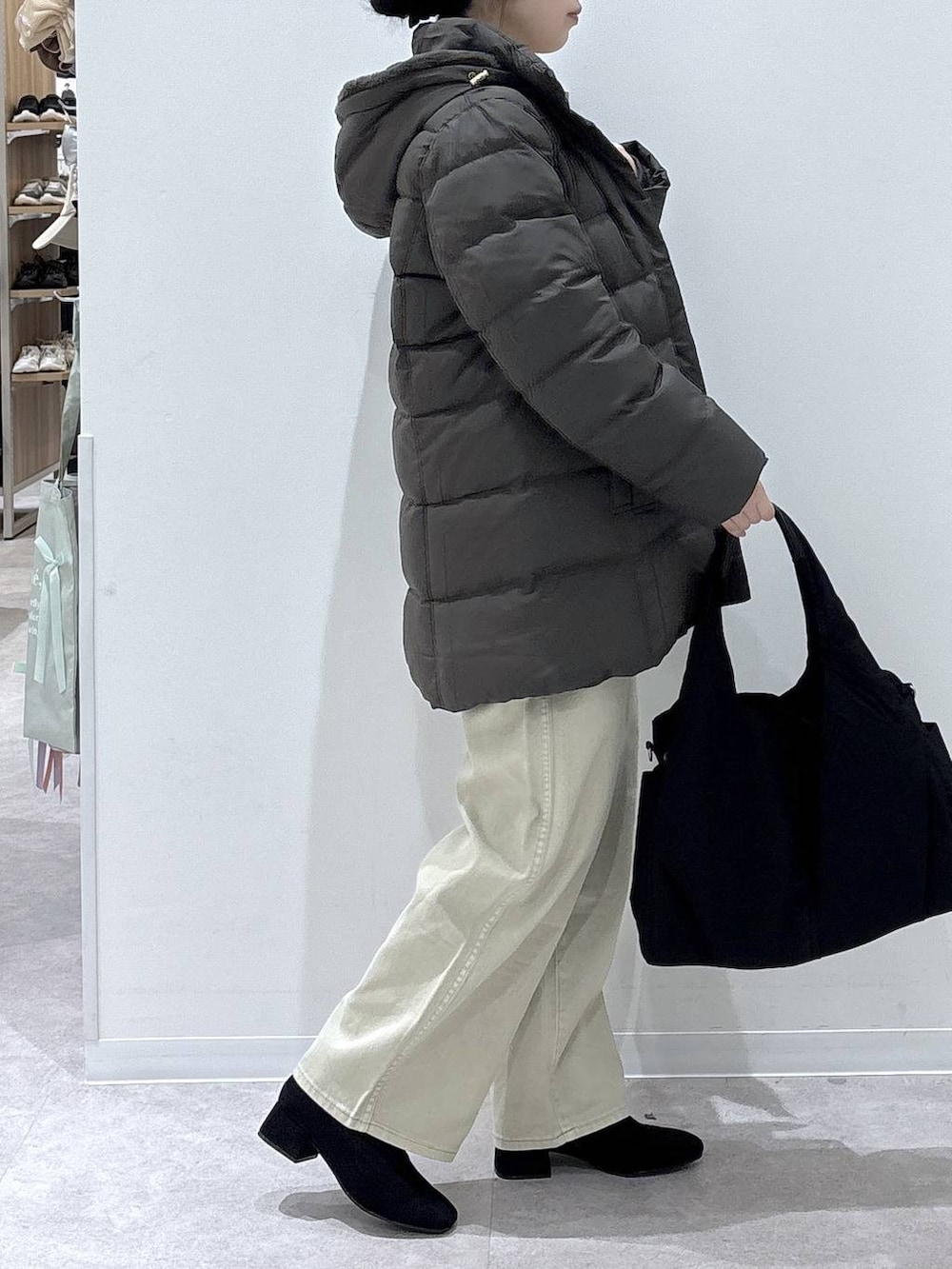 ブラック系のトートバッグ、ブラウン系のダウンジャケット/コート、ベージュ系のデニムパンツを着用したレディースの冬コーディネートの2枚目の写真