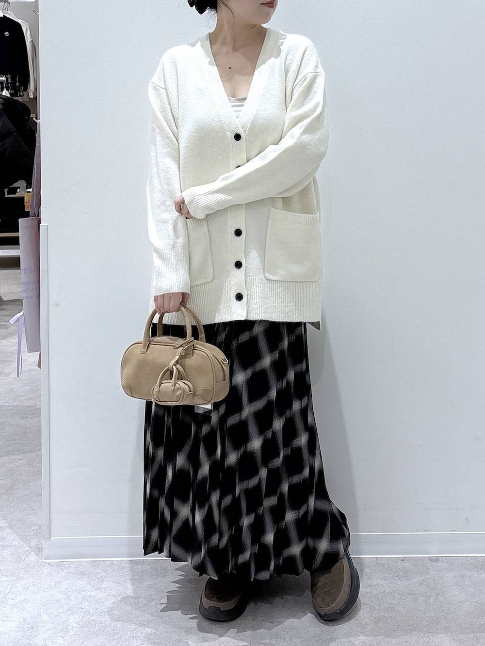 ホワイト系のカーディガン/ボレロ、ブラウン系のブーツ、ブラック系のスカートを着用したレディースの冬コーディネートの4枚目の写真