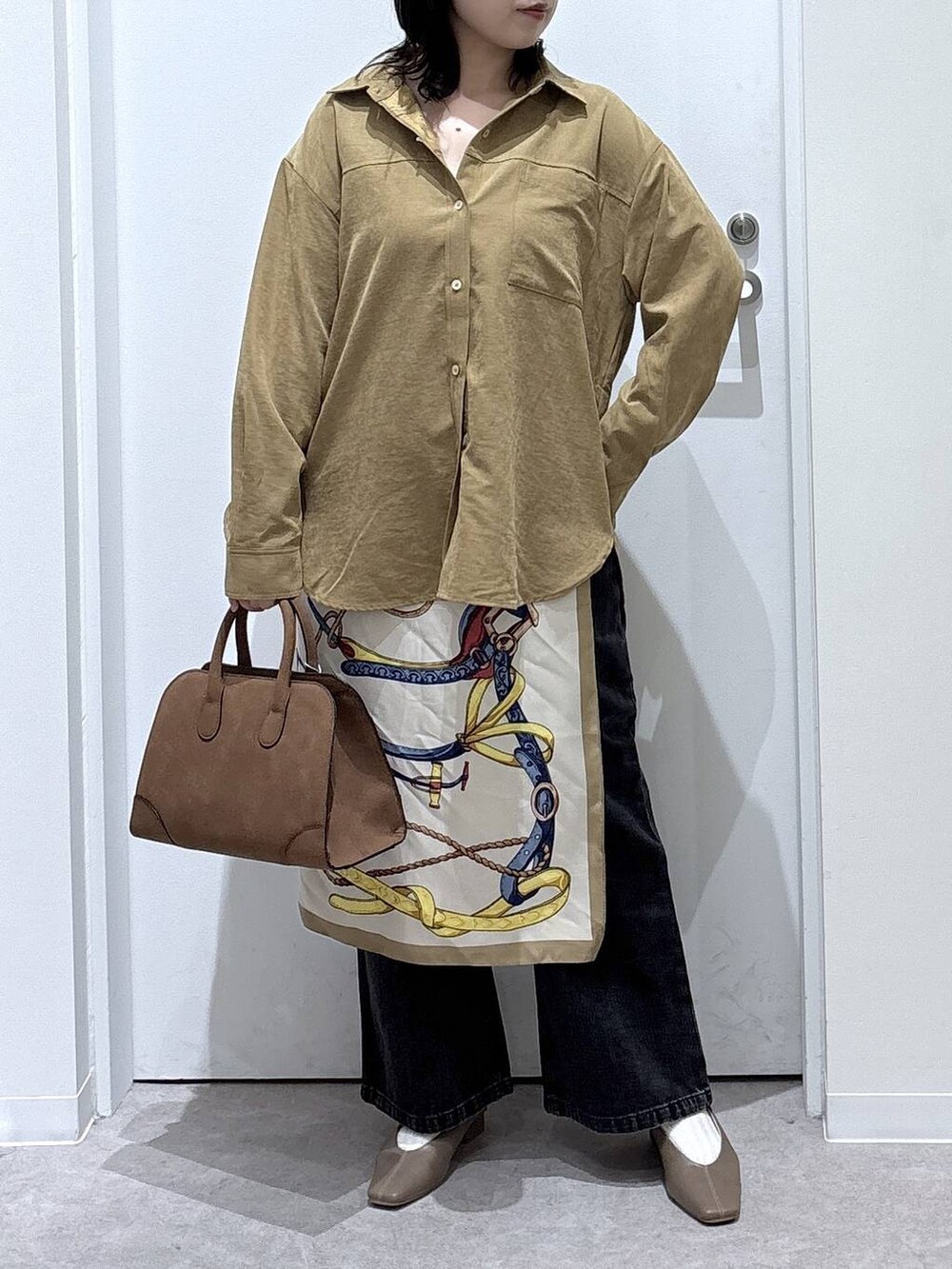 ブラック系のデニムパンツ、イエロー系のシャツ/ブラウス、ベージュ系のショルダーバッグを着用したレディースの秋コーディネートの5枚目の写真