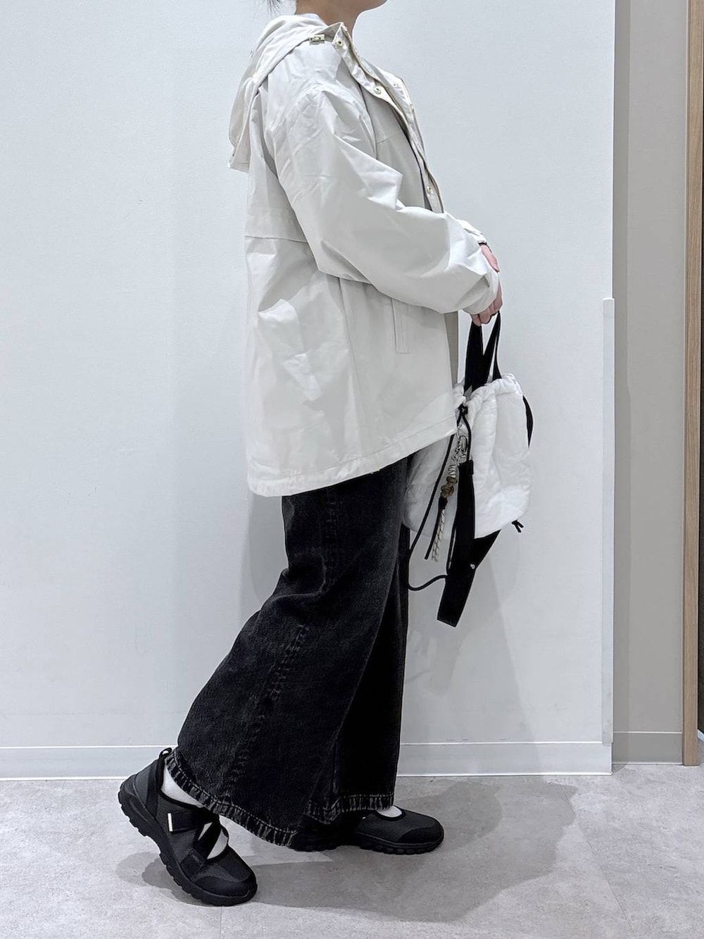 ブラック系のデニムパンツ、ホワイト系のハンドバッグ、ベージュ系のパーカーを着用したレディースの春コーディネートの2枚目の写真