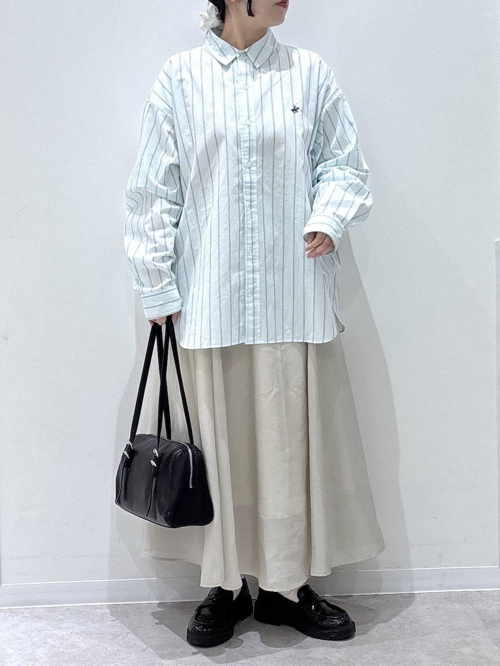 ベージュ系のスカート、ブラック系のショルダーバッグ、ブルー系のシャツ/ブラウスを着用したレディースの春コーディネートの4枚目の写真