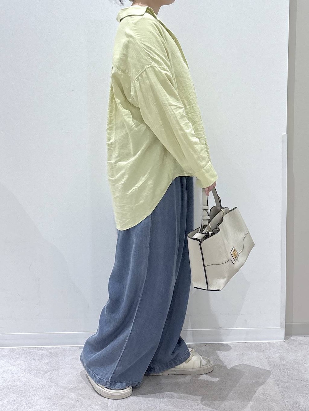 イエロー系のシャツ/ブラウス、ベージュ系のショルダーバッグ、ブルー系のデニムパンツを着用したレディースの春コーディネートの2枚目の写真