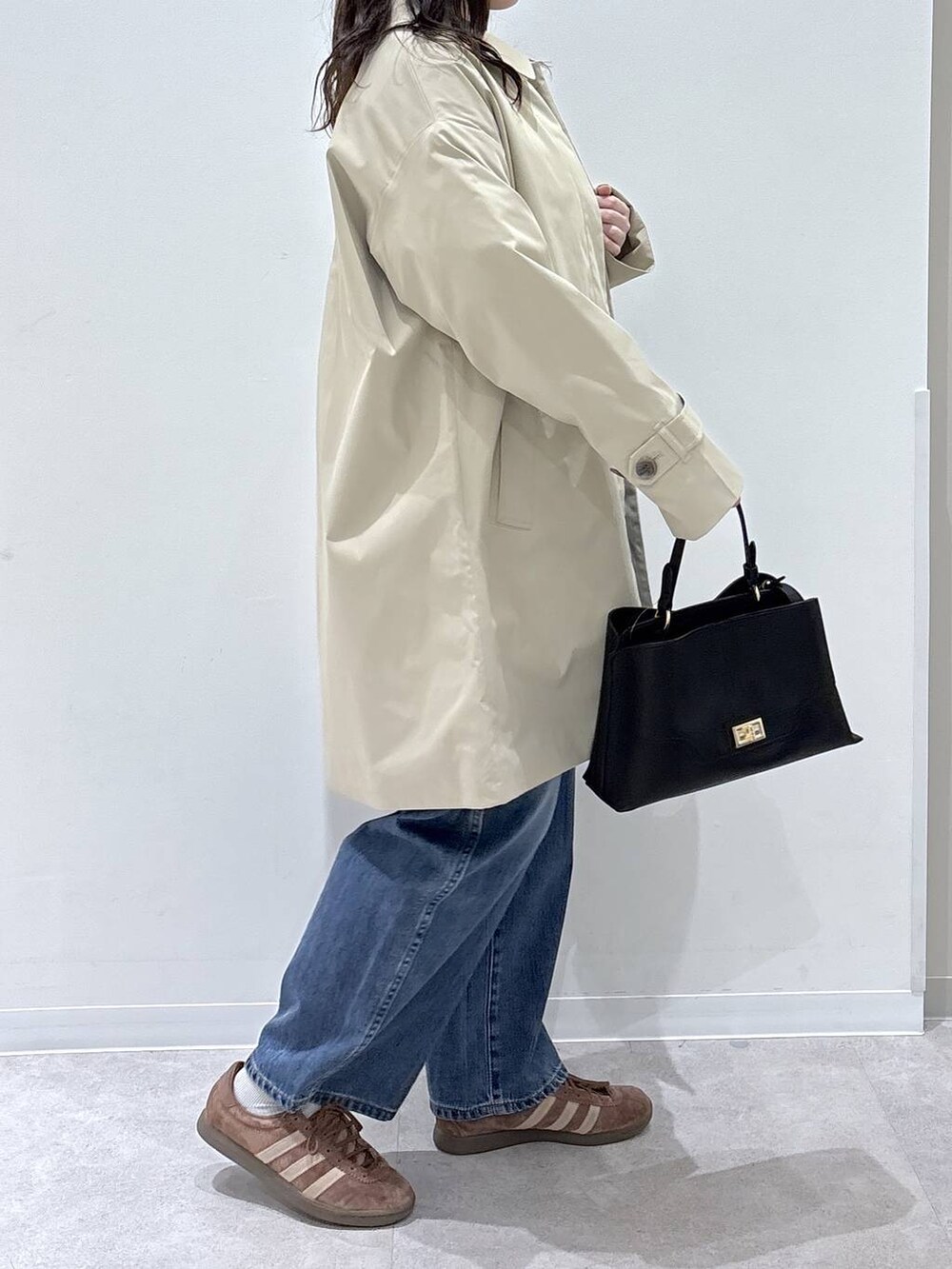 ブルー系のデニムパンツ、ベージュ系のスウェット、ブラック系のショルダーバッグを着用したレディースの春コーディネートの2枚目の写真