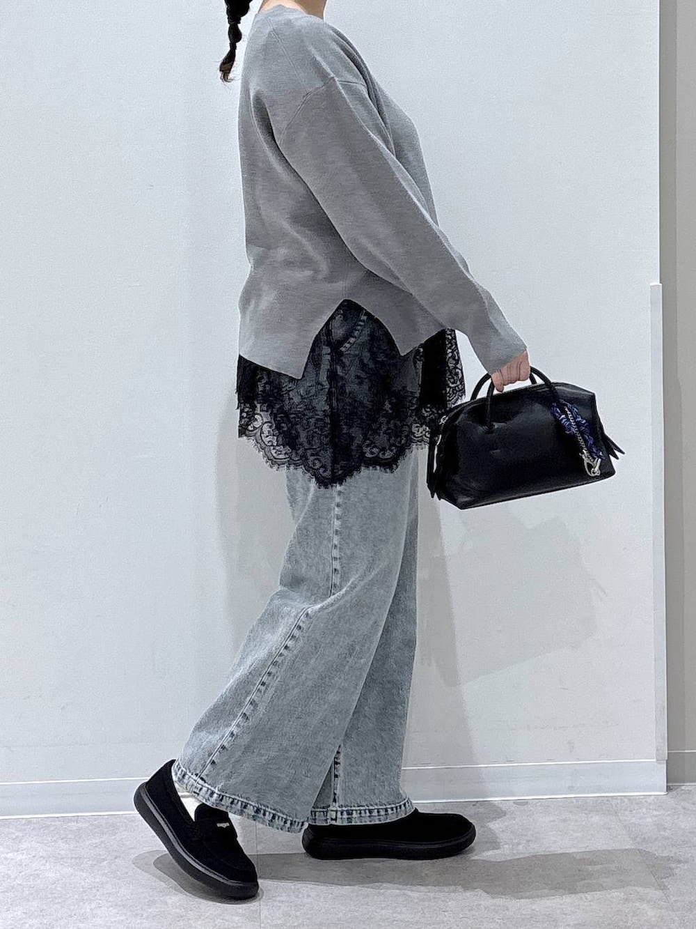 ブルー系のデニムパンツ、グレー系のニット/セーター、ブラック系のスニーカーを着用したレディースの春コーディネートの2枚目の写真