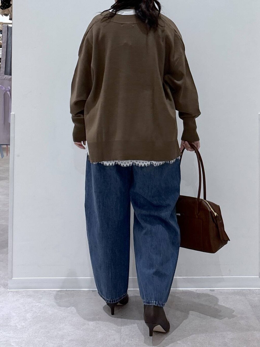 ブラウン系のボストンバッグ、ホワイト系のTシャツ/カットソー、ブラウン系のブーツを着用したレディースの冬コーディネートの3枚目の写真