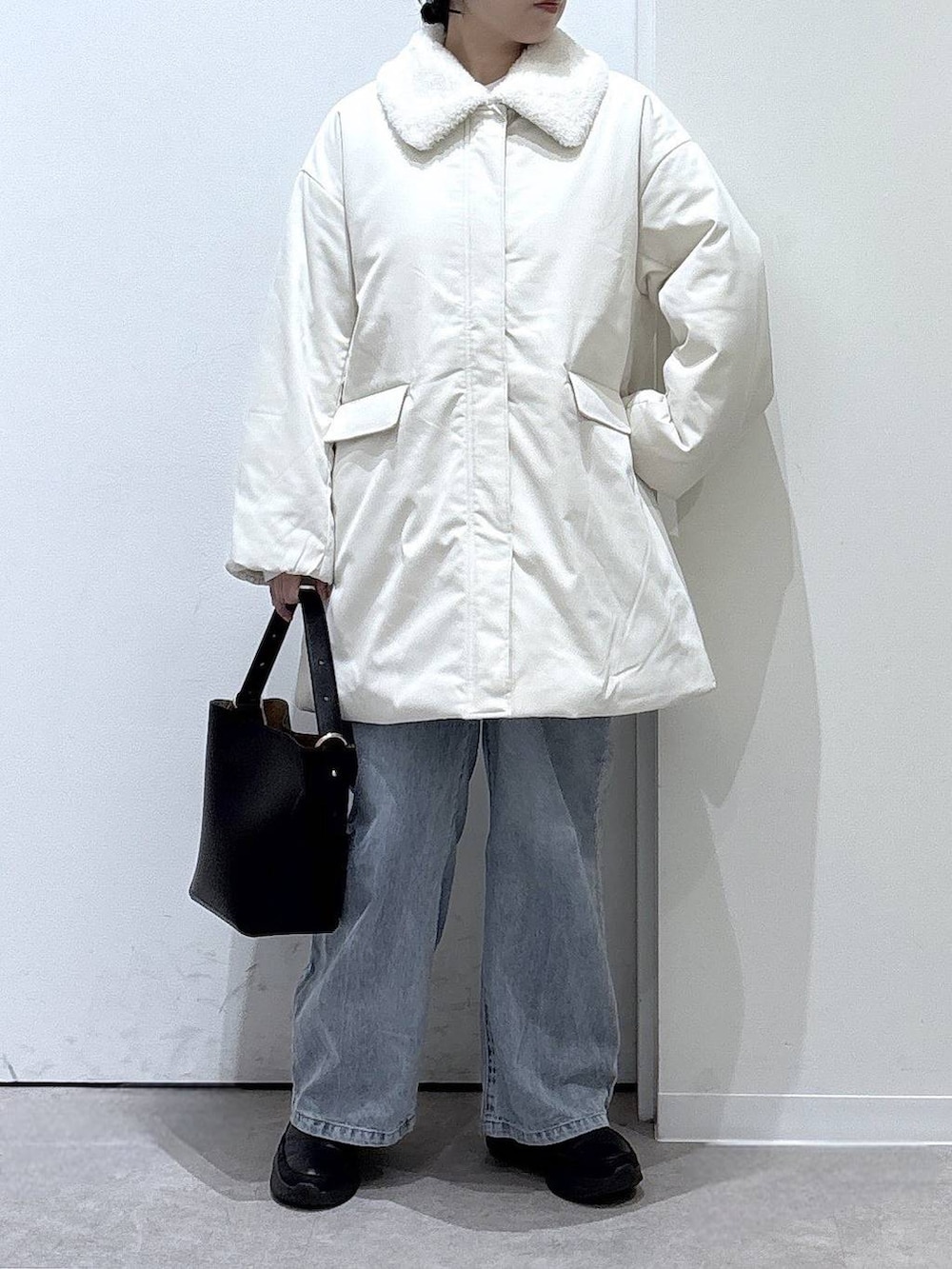 ブラック系のショルダーバッグ、ブルー系のデニムパンツ、ブラック系のブーツを着用したレディースの秋コーディネートの4枚目の写真