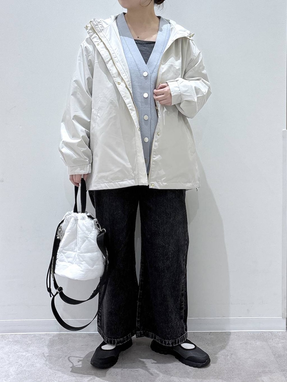 ブラック系のデニムパンツ、ホワイト系のハンドバッグ、ベージュ系のパーカーを着用したレディースの春コーディネートの4枚目の写真