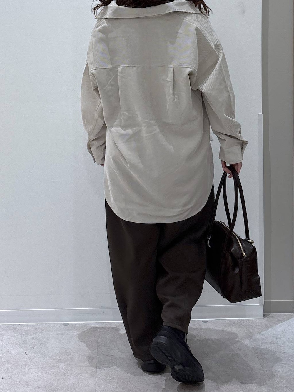 ホワイト系のTシャツ/カットソー、ブラック系のブーツ、ブラウン系のボストンバッグを着用したレディースの秋コーディネートの3枚目の写真