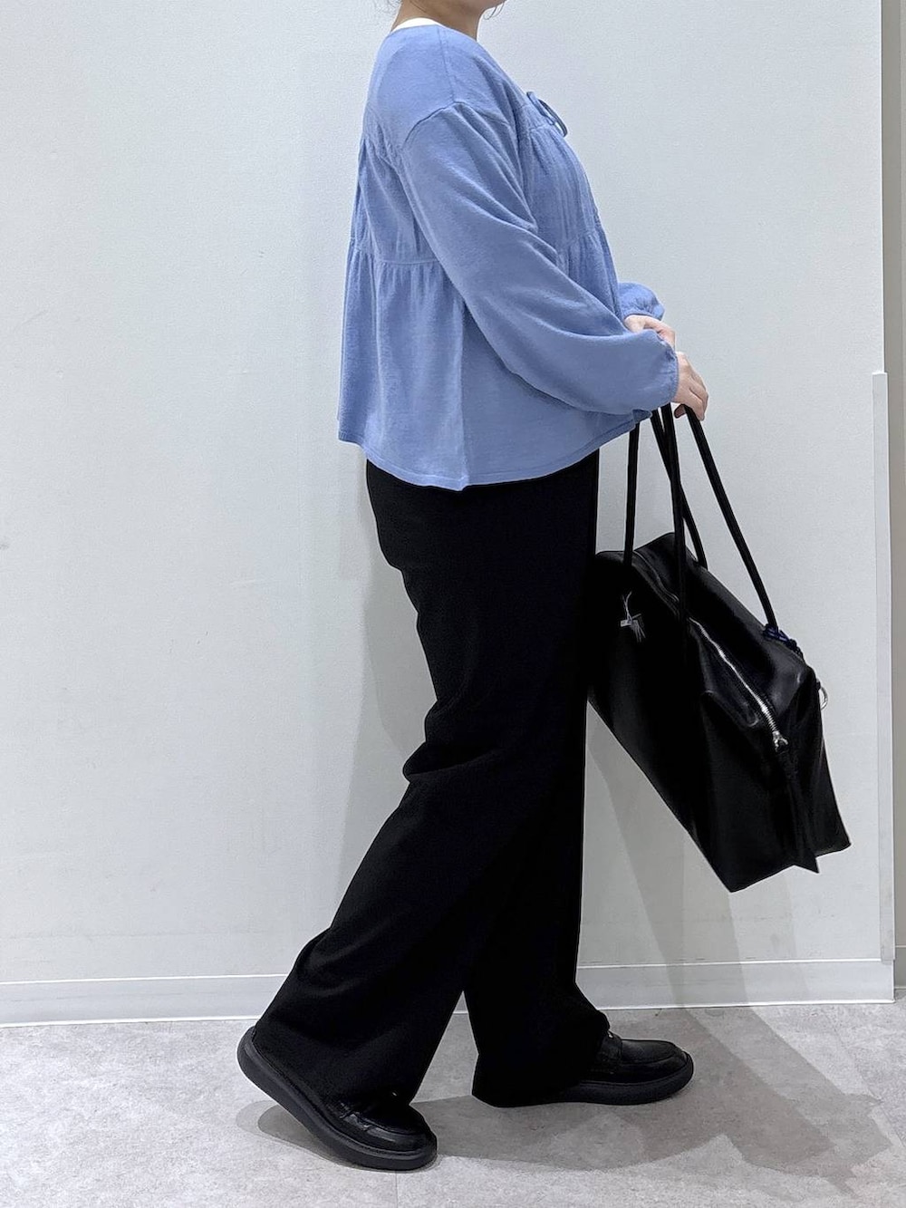 ブラック系のボストンバッグ、ブラック系のスラックス、ブルー系のカーディガン/ボレロを着用したレディースの春コーディネートの2枚目の写真