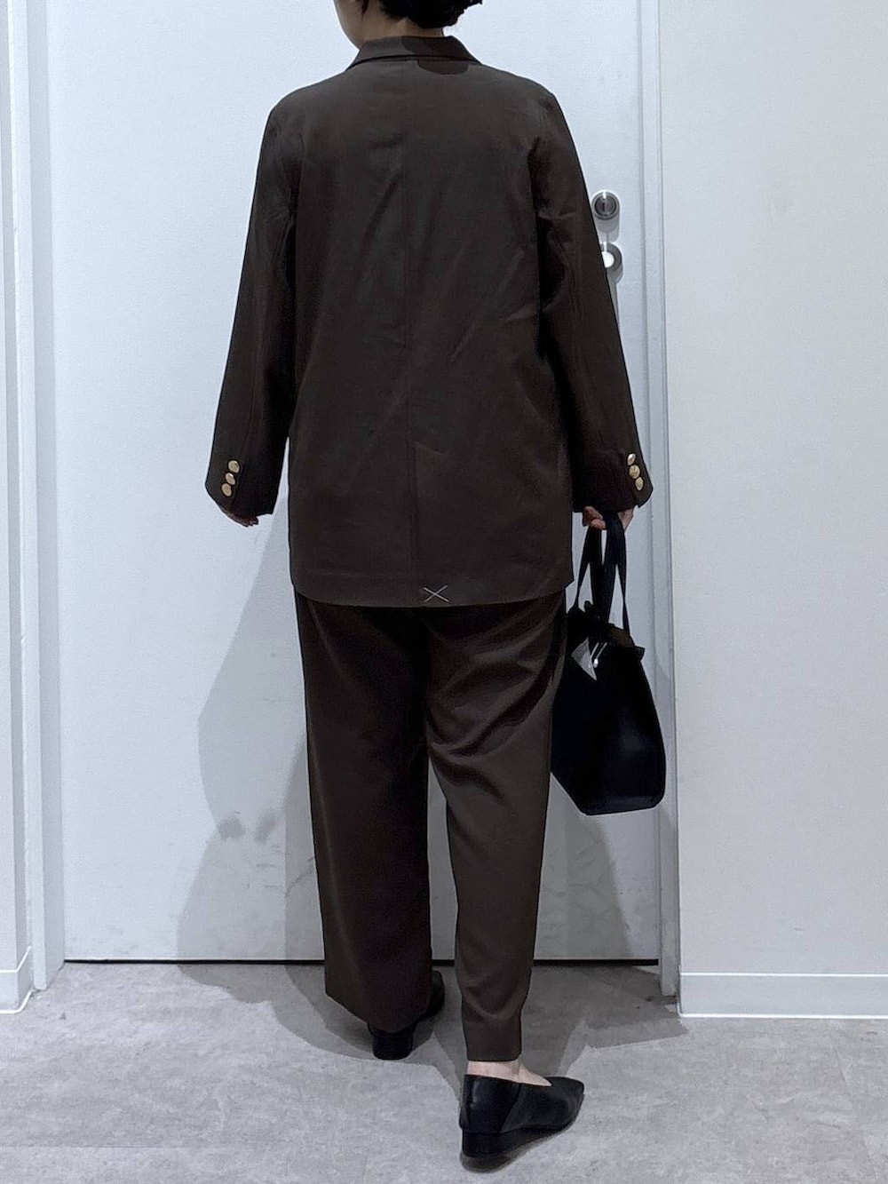 ブラック系のショルダーバッグ、ブラウン系のテーラードジャケット、ブラウン系のスラックスを着用したレディースの秋コーディネートの3枚目の写真