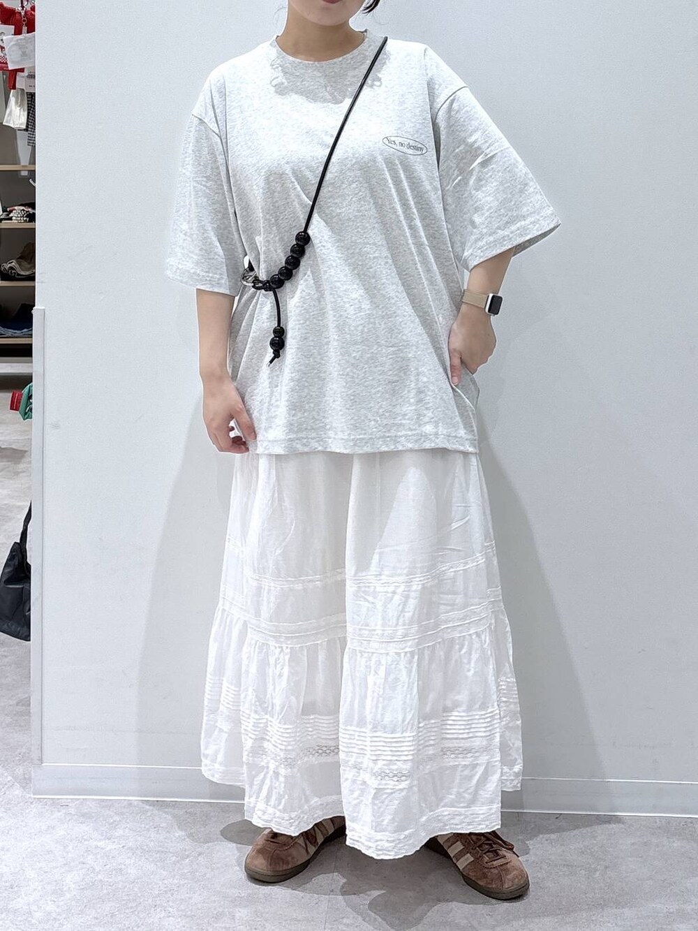 ホワイト系のスカート、グレー系のTシャツ/カットソー、ブラック系のスマホグッズを着用したレディースの夏コーディネートの3枚目の写真