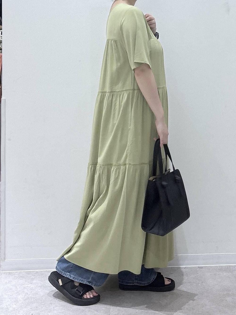 ブラック系のショルダーバッグ、ブルー系のデニムパンツ、ブラック系のサンダルを着用したレディースの夏コーディネートの2枚目の写真