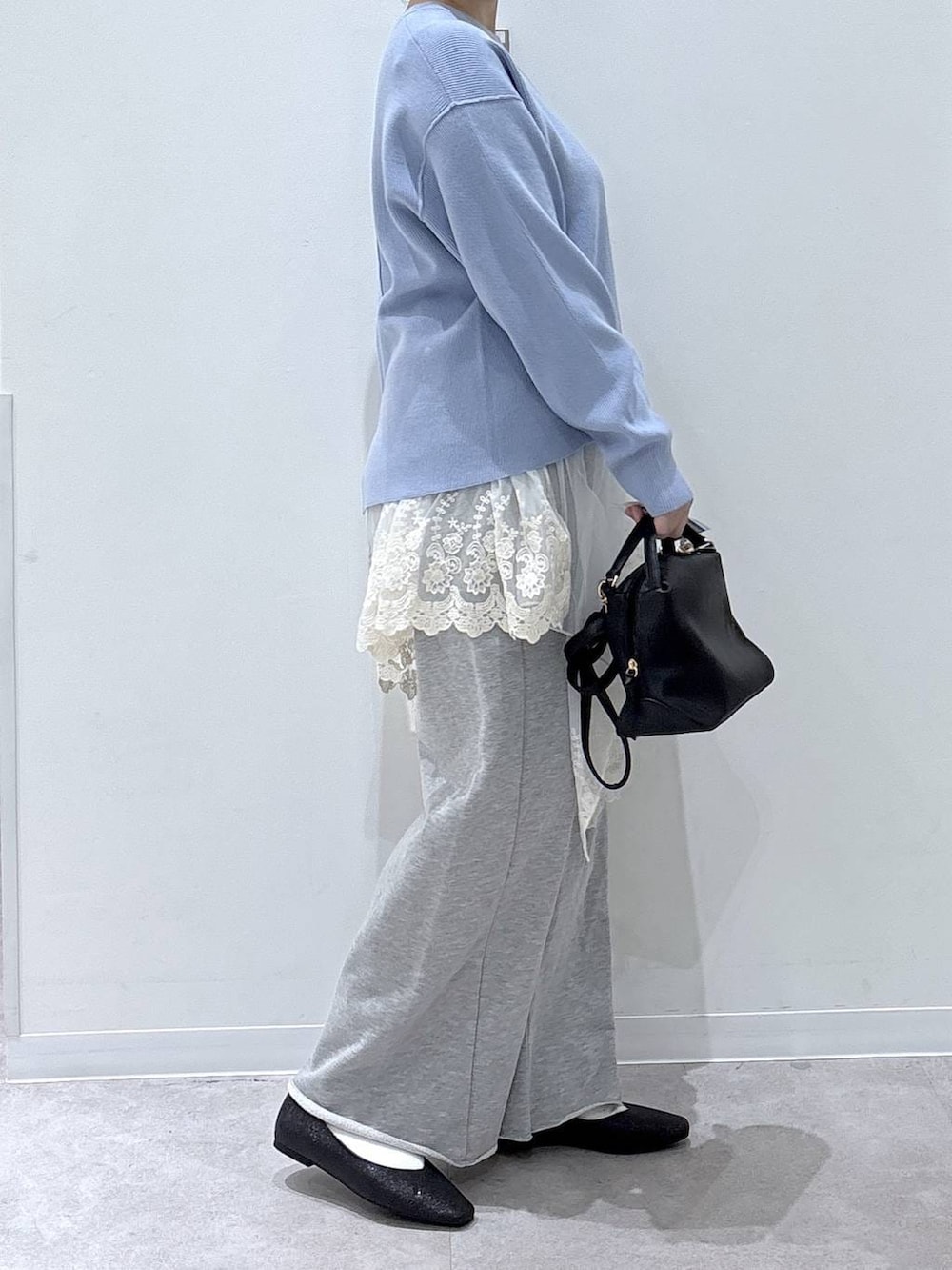 ブラック系のパンプス、ブルー系のニット/セーター、グレー系のスウェットパンツを着用したレディースの冬コーディネートの2枚目の写真