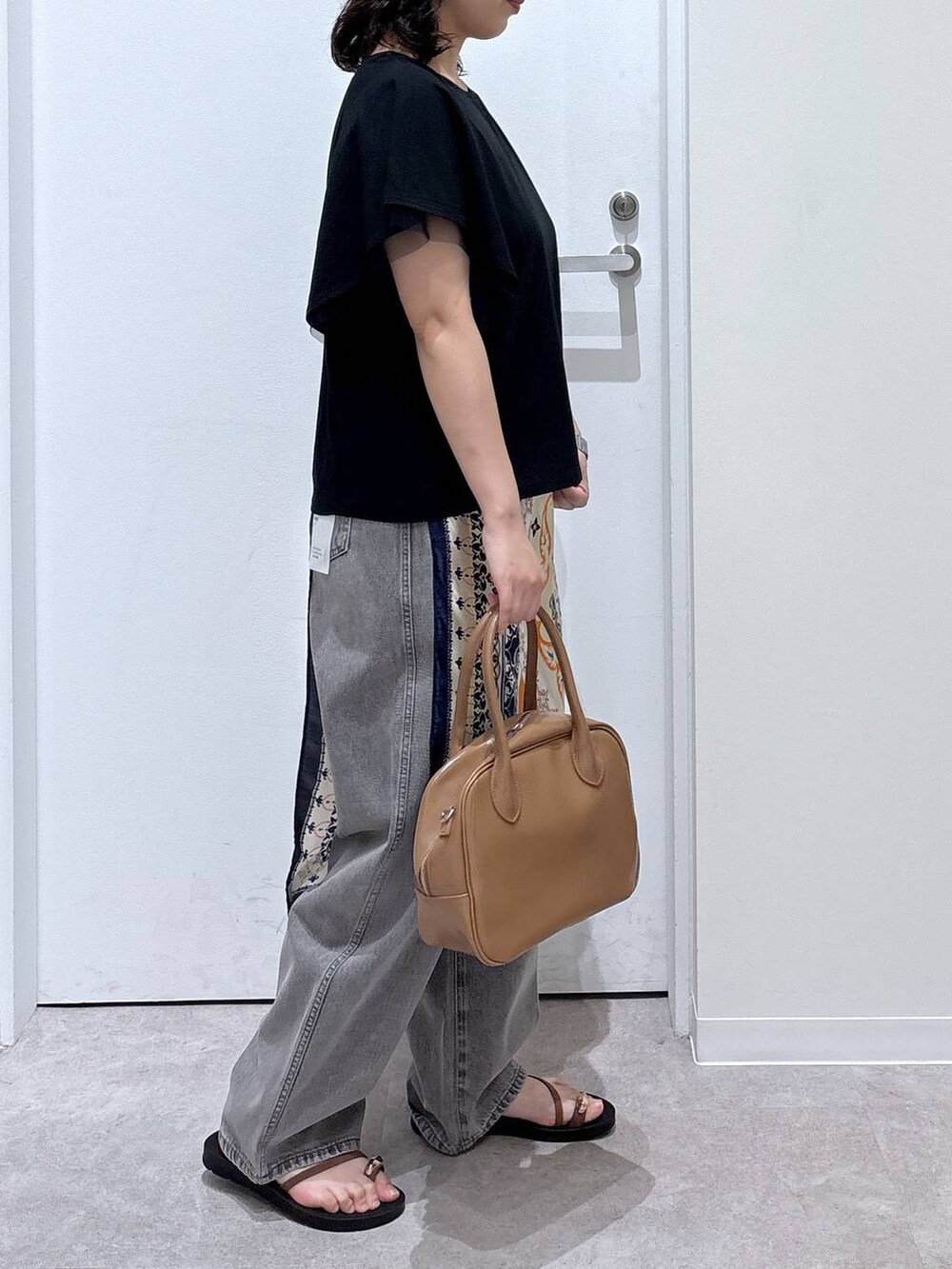 グレー系のデニムパンツ、ベージュ系のボストンバッグ、ブラック系のTシャツ/カットソーを着用したレディースの夏コーディネートの2枚目の写真