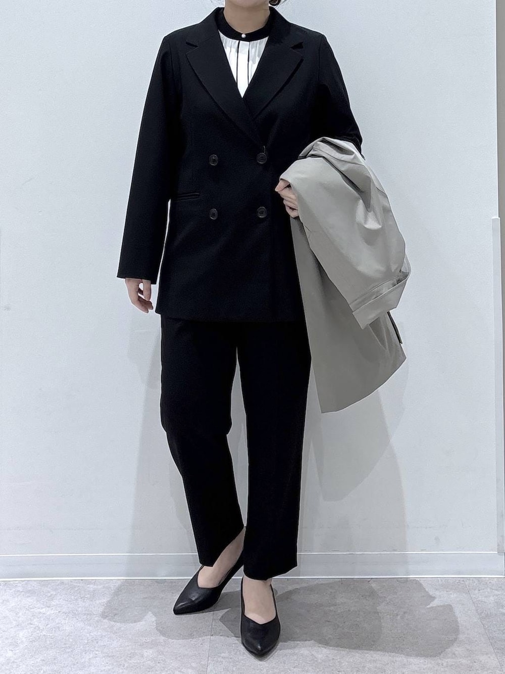 ブラック系のパンプス、ブラック系のスラックス、ホワイト系のシャツ/ブラウスを着用したレディースの冬コーディネートの3枚目の写真