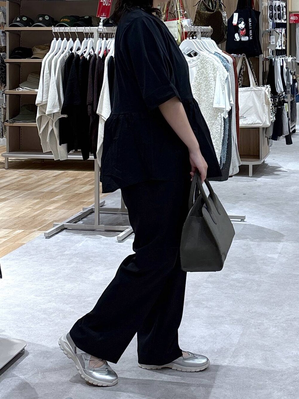 グレー系のスニーカー、ブラック系のスラックス、グリーン系のショルダーバッグを着用したレディースの秋コーディネートの2枚目の写真