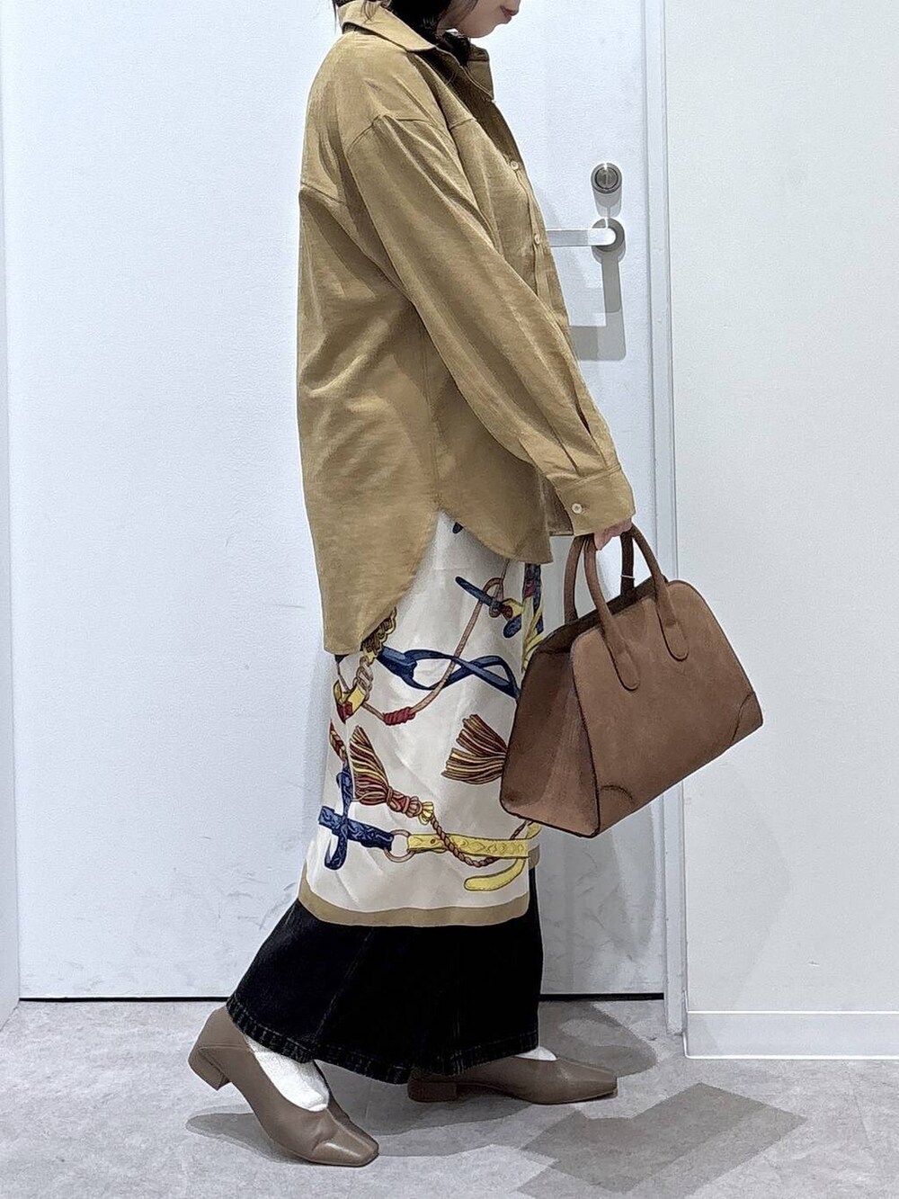 ブラック系のデニムパンツ、イエロー系のシャツ/ブラウス、ベージュ系のショルダーバッグを着用したレディースの秋コーディネートの2枚目の写真