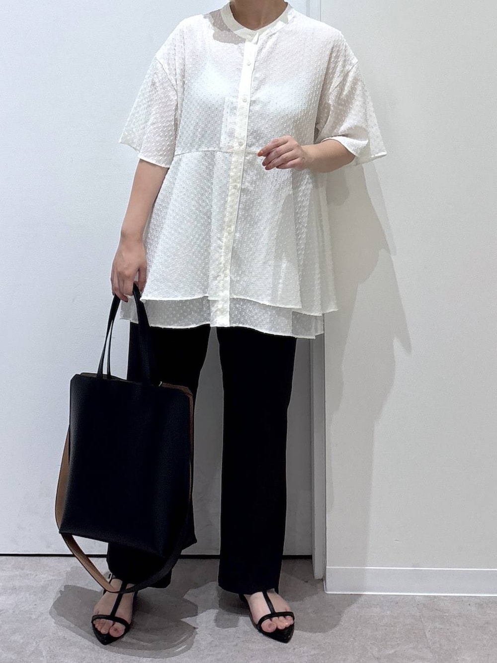 ブラック系のトートバッグ、ブラウン系のスラックス、ブラック系のサンダルを着用したレディースの夏コーディネートの4枚目の写真