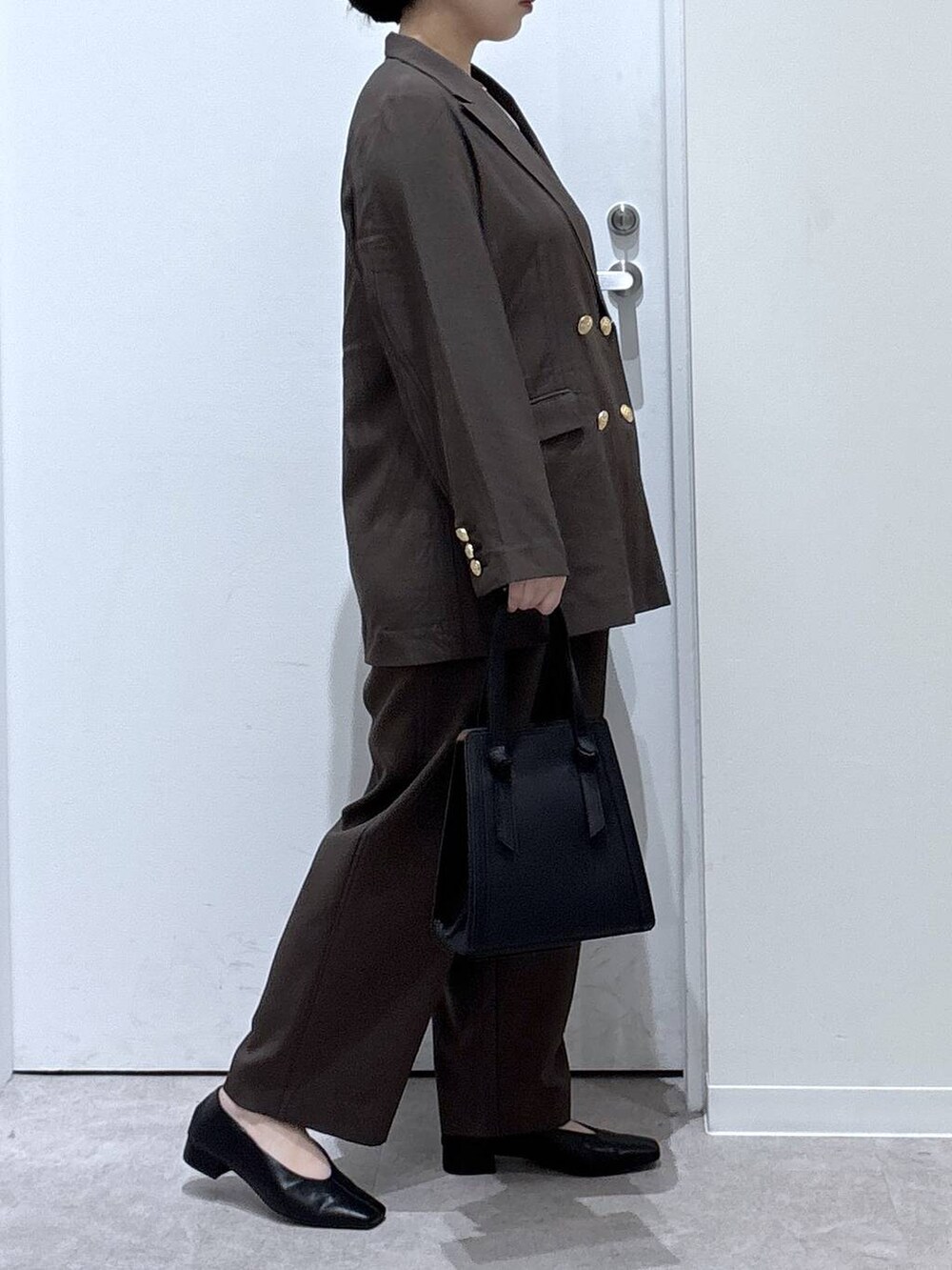 ブラック系のショルダーバッグ、ブラウン系のテーラードジャケット、ブラウン系のスラックスを着用したレディースの秋コーディネートの2枚目の写真