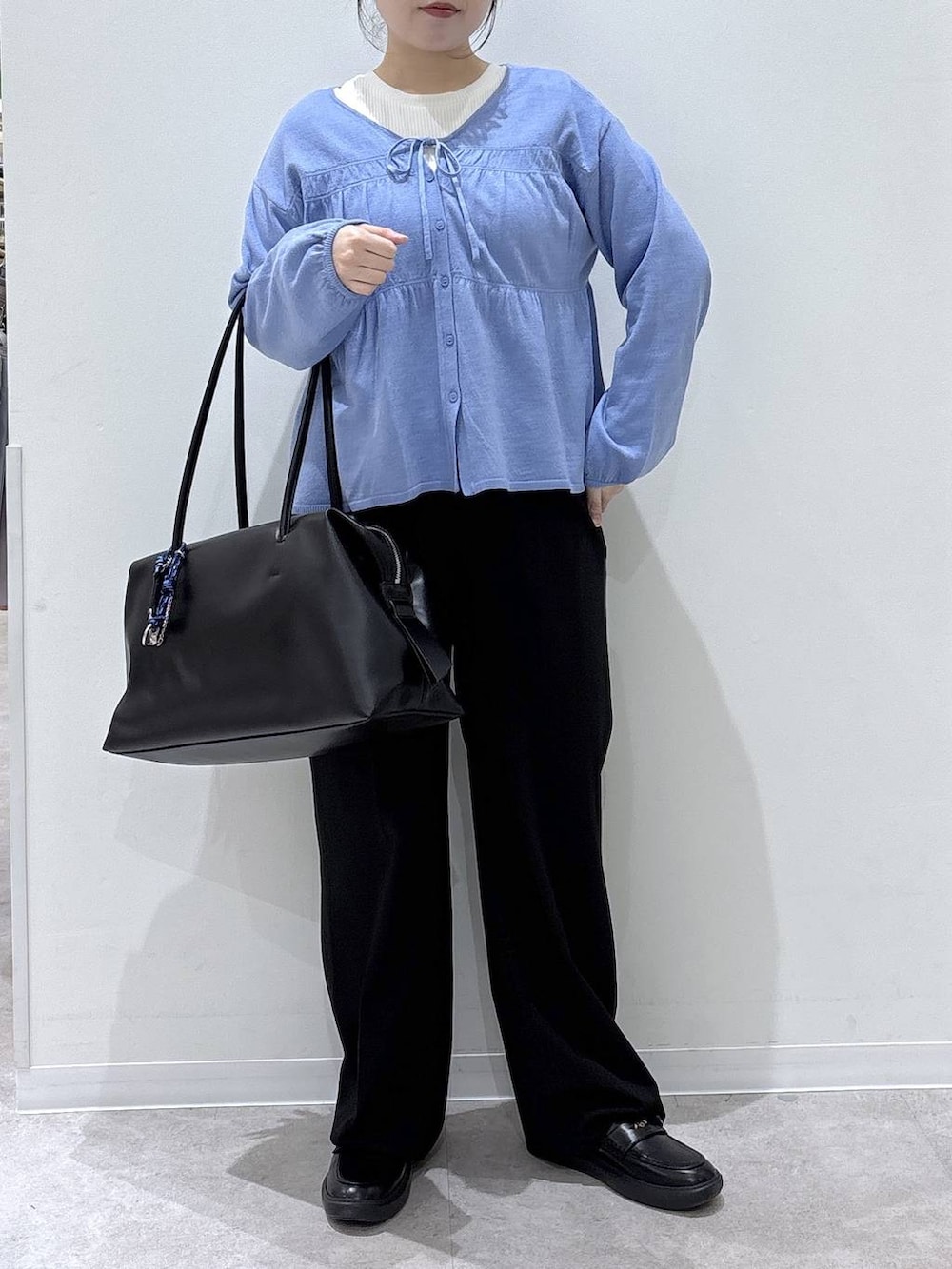 ブラック系のボストンバッグ、ブラック系のスラックス、ブルー系のカーディガン/ボレロを着用したレディースの春コーディネートの4枚目の写真