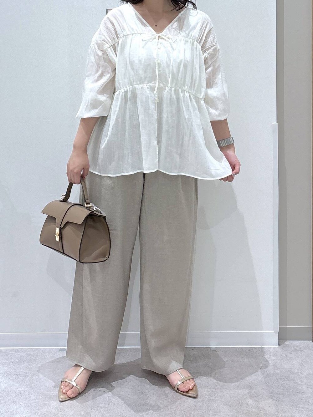 ベージュ系のショルダーバッグ、ベージュ系のその他パンツ、ゴールド系のサンダルを着用したレディースの夏コーディネートの4枚目の写真