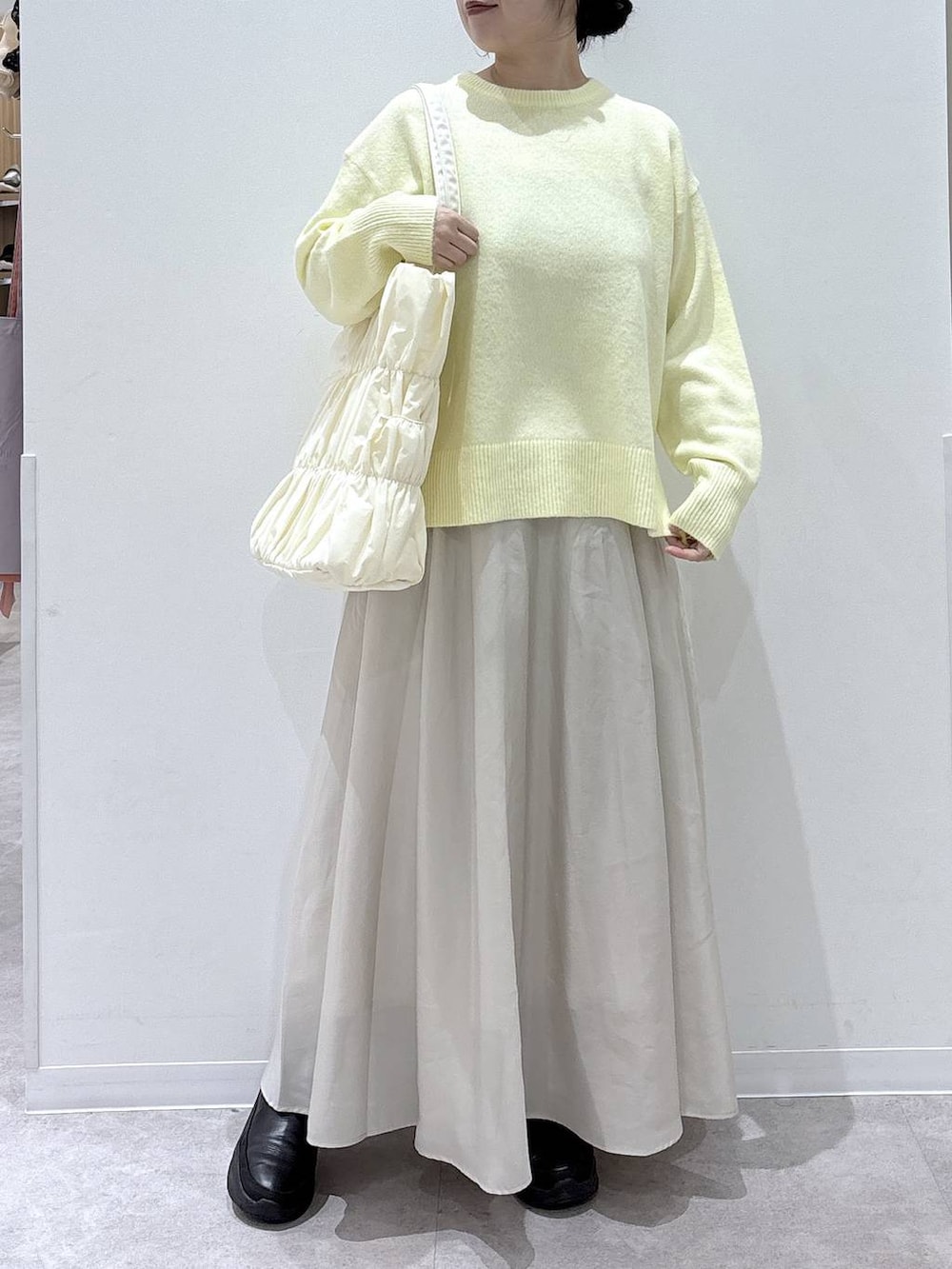 ベージュ系のトートバッグ、イエロー系のニット/セーター、ブラック系のブーツを着用したレディースの冬コーディネートの4枚目の写真