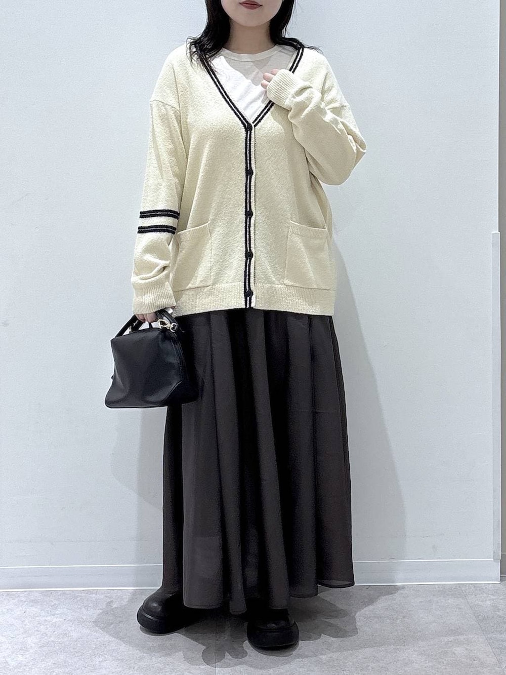 ブラック系のショルダーバッグ、ブラウン系のスカートを着用したレディースの冬コーディネートの4枚目の写真