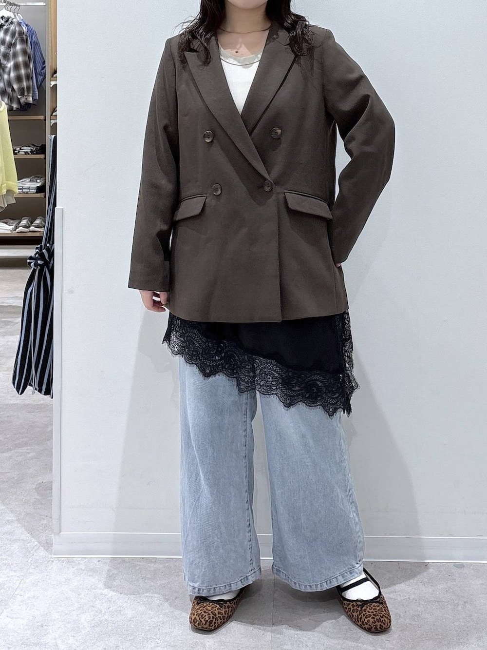 ブルー系のデニムパンツ、ブラウン系のテーラードジャケット、ゴールド系のネックレスを着用したレディースの春コーディネートの5枚目の写真