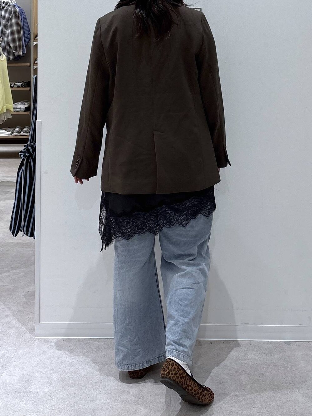 ブルー系のデニムパンツ、ブラウン系のテーラードジャケット、ゴールド系のネックレスを着用したレディースの春コーディネートの3枚目の写真