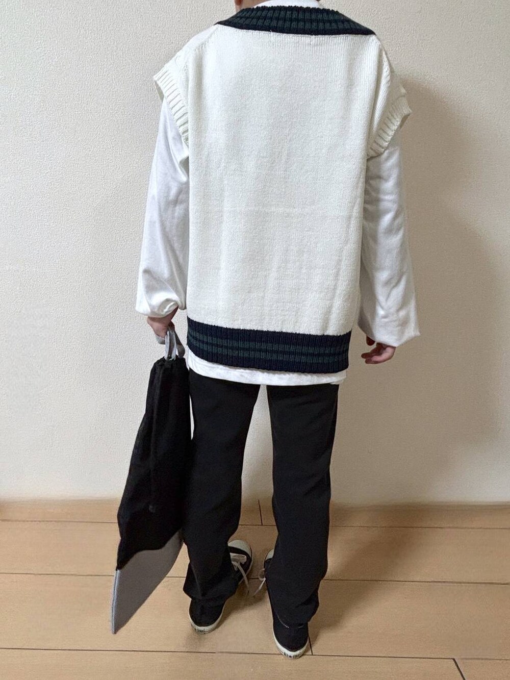 ブラック系のデニムパンツ、ベージュ系のベスト、ブラック系のハンドバッグを着用したキッズの冬コーディネートの3枚目の写真