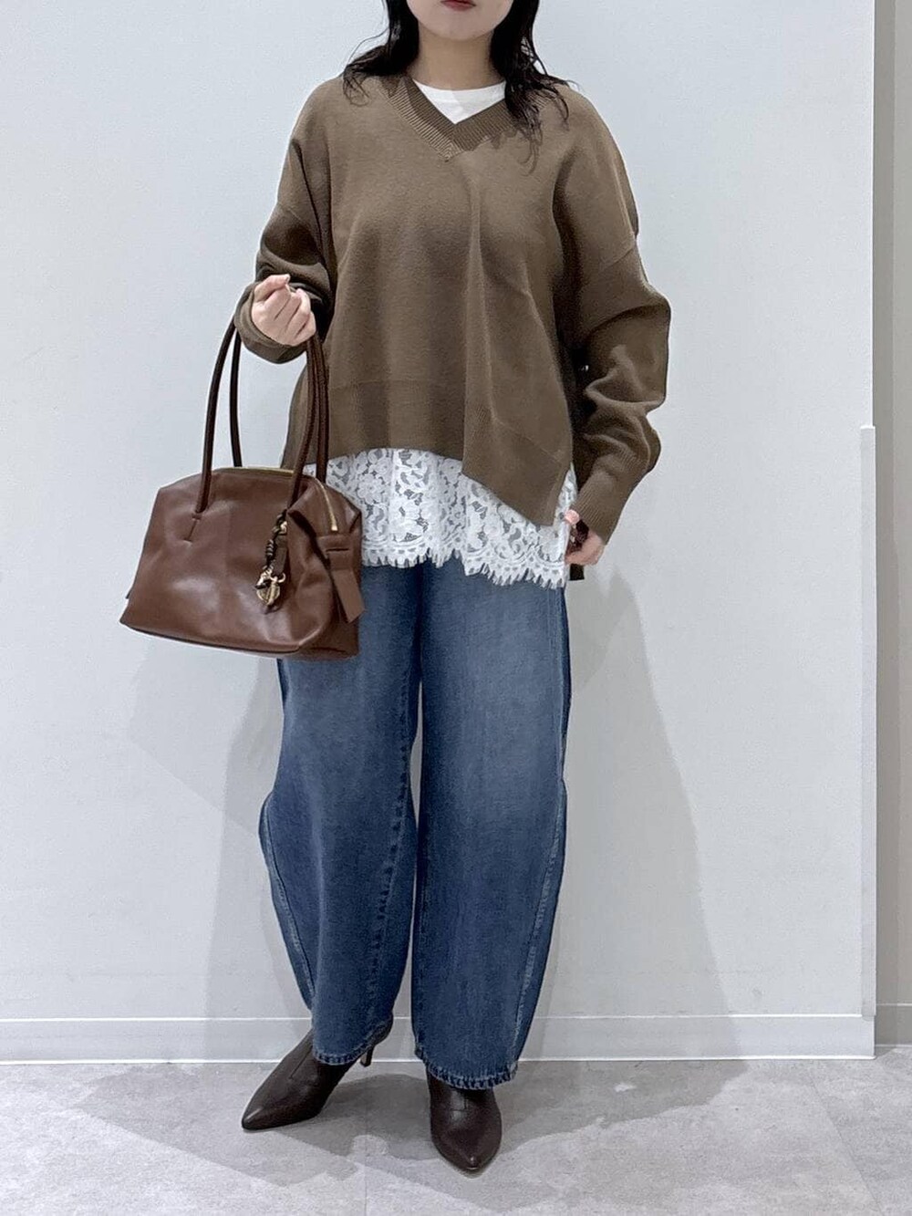 ブラウン系のボストンバッグ、ホワイト系のTシャツ/カットソー、ブラウン系のブーツを着用したレディースの冬コーディネートの4枚目の写真