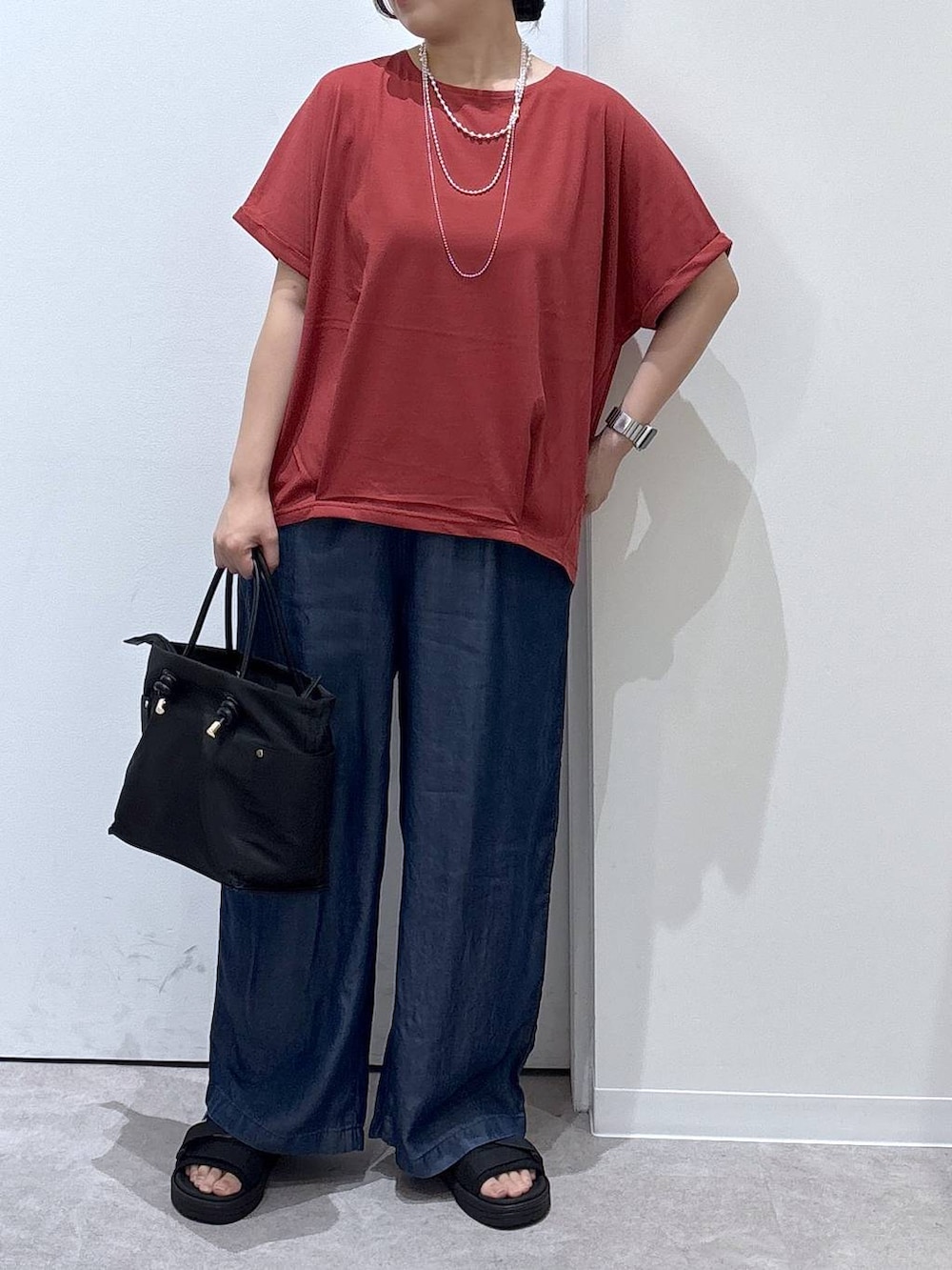 ブラック系のトートバッグ、ブラック系のサンダル、ブルー系のデニムパンツを着用したレディースの夏コーディネートの3枚目の写真